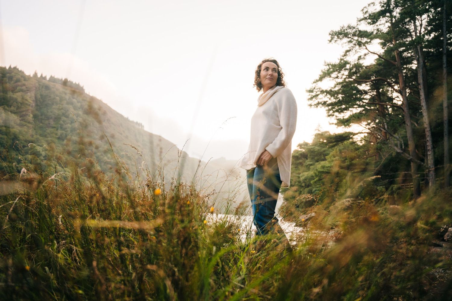 Family photographer Ireland Dublin Person standing on hillside trail overlooking misty mountain valley at sunrise.