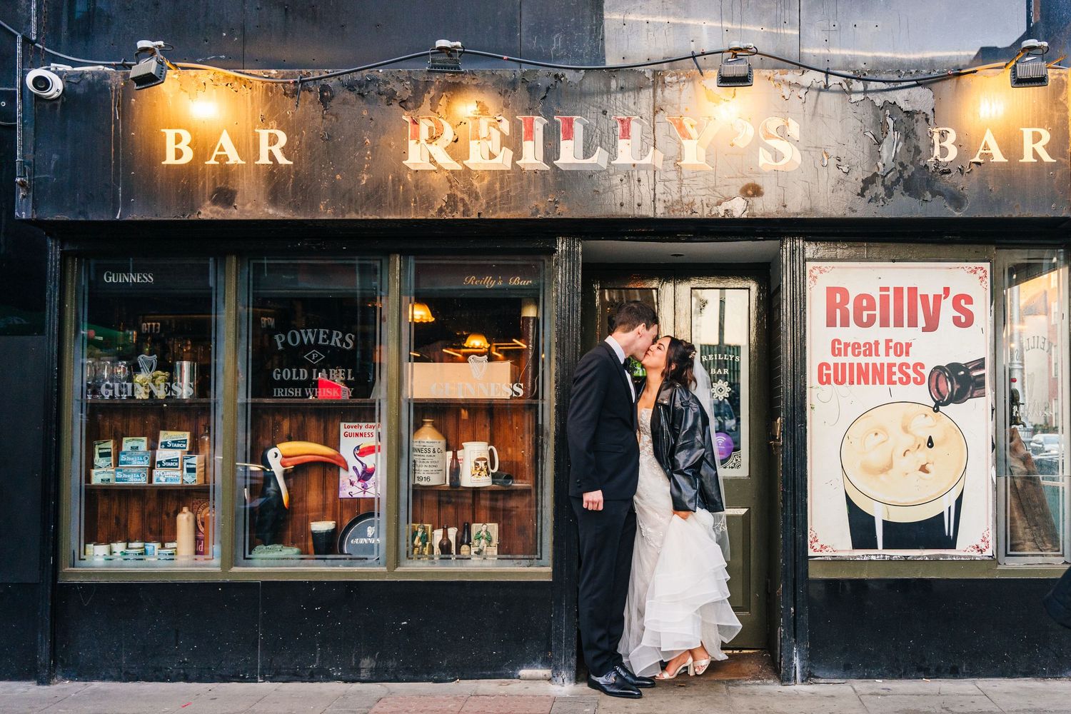 Romantic evening wedding photo outside Reilly's Bar with vintage storefront signage. Wedding PHOTOGRAPHER Dublin