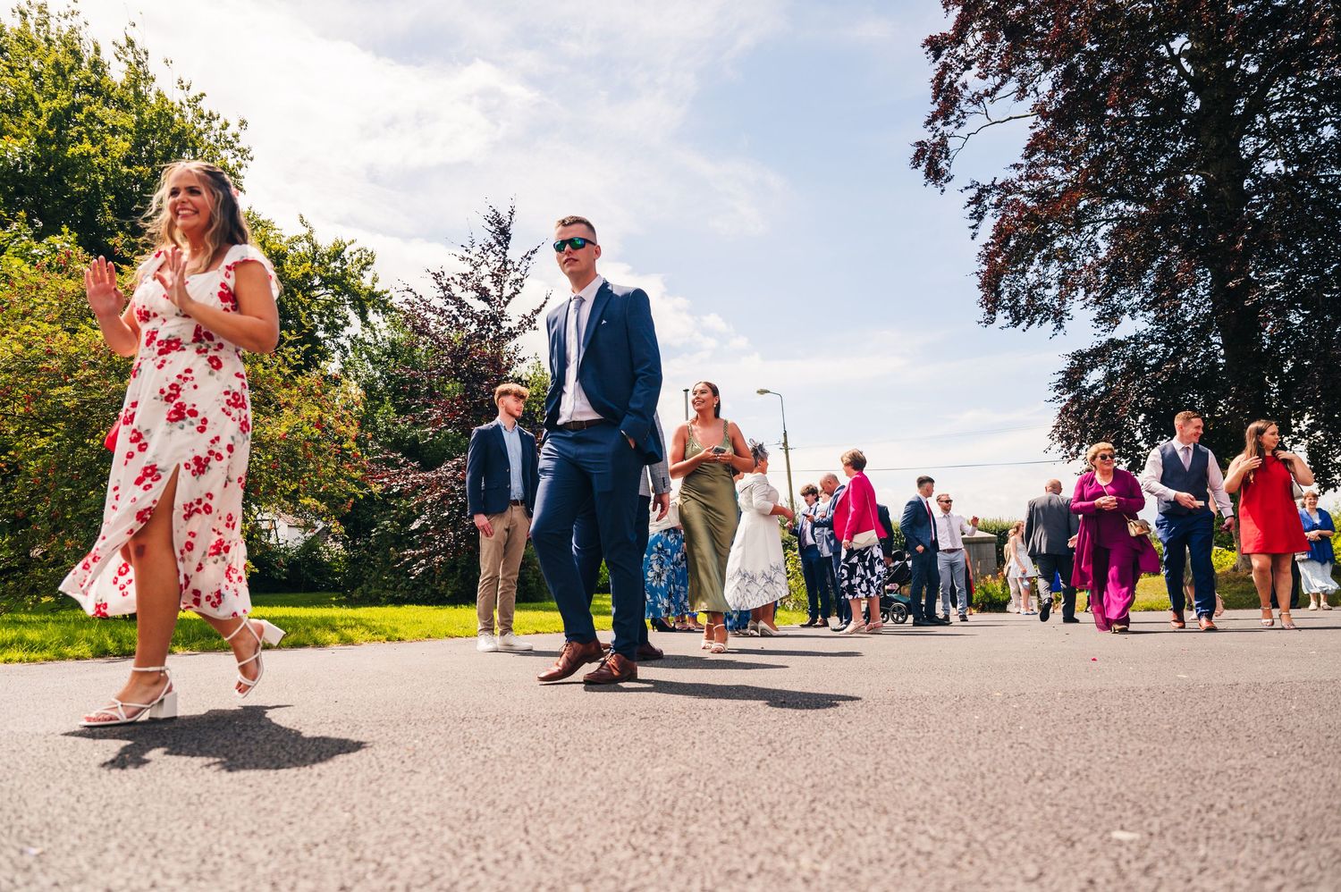 Millhouse slane wedding photographer dublinWedding guests walking along curved pathway during outdoor celebration.
