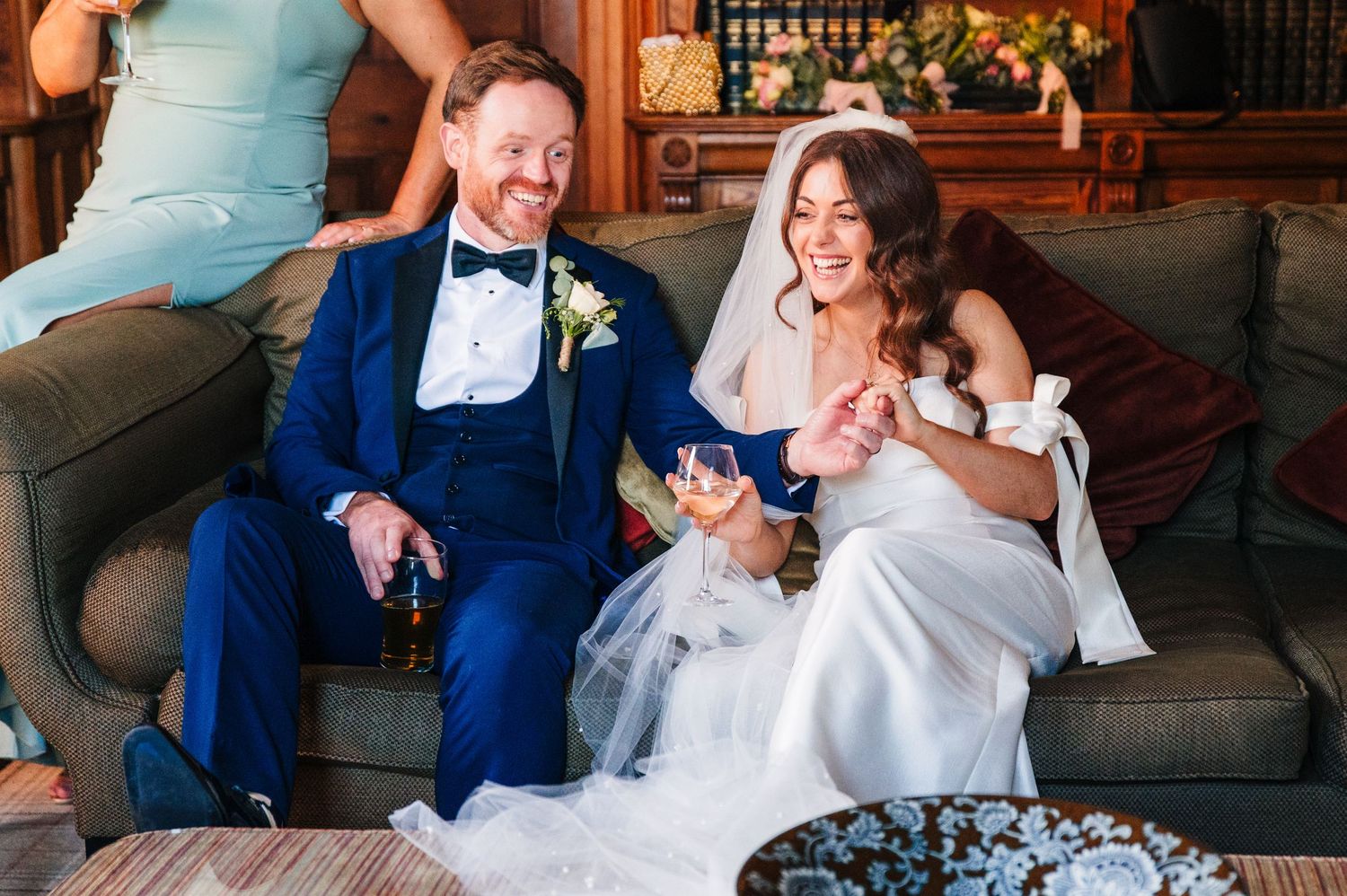 Castle Leslie Wedding Photographer Dublin Couple shares a lighthearted moment while relaxing on a couch during their wedding celebration.