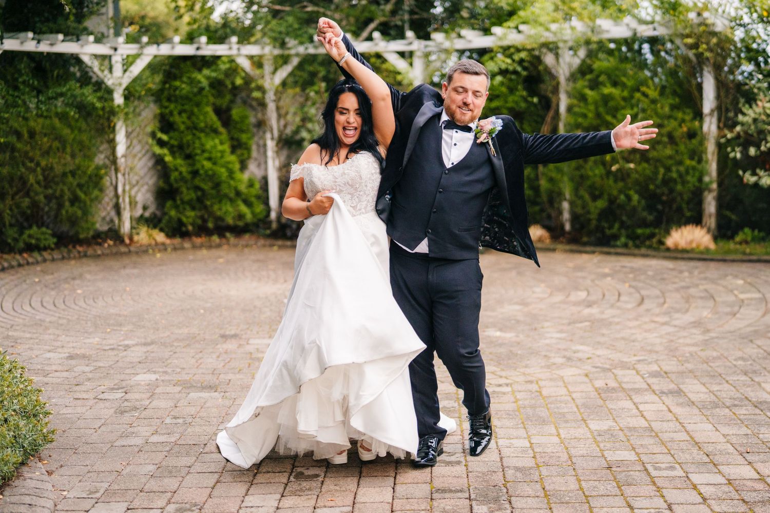 Elegant wedding party walks arm-in-arm down a stone pathway in a garden setting.  photographer Dublin