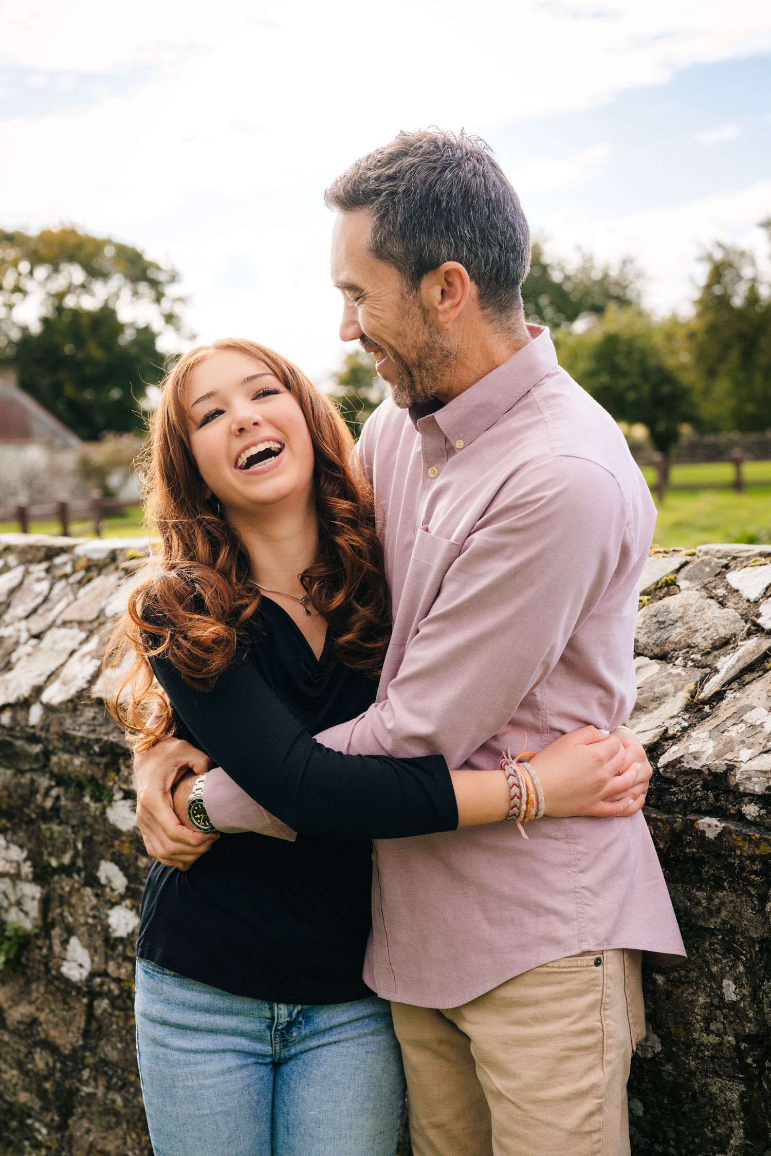 Couple sharing candid laughs while leaning against an old stone wall. BEctive abbey family photographer dublin