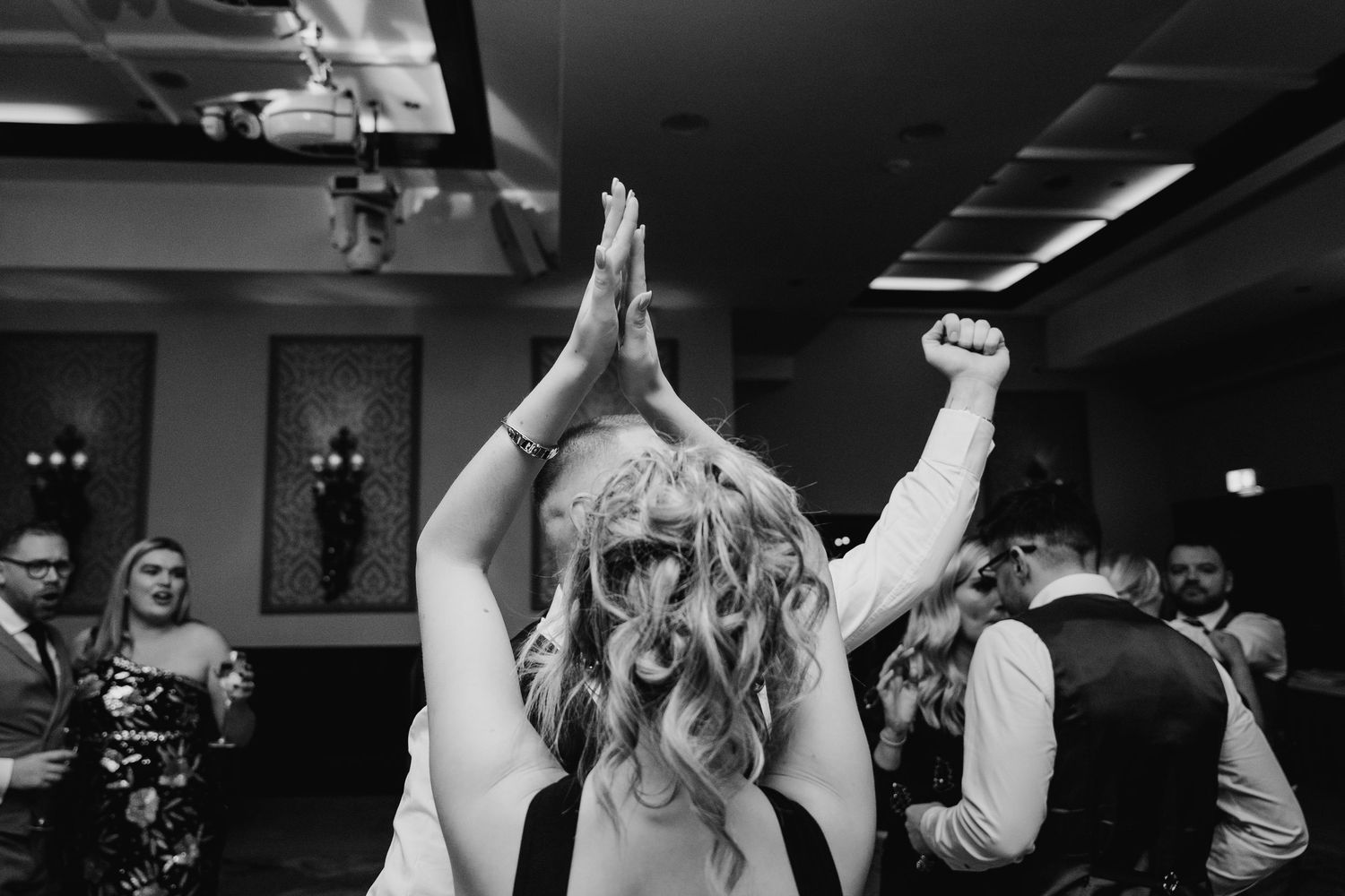 A black and white photo of wedding celebrations with energetic dancing and raised arms. Wedding photographer dublin