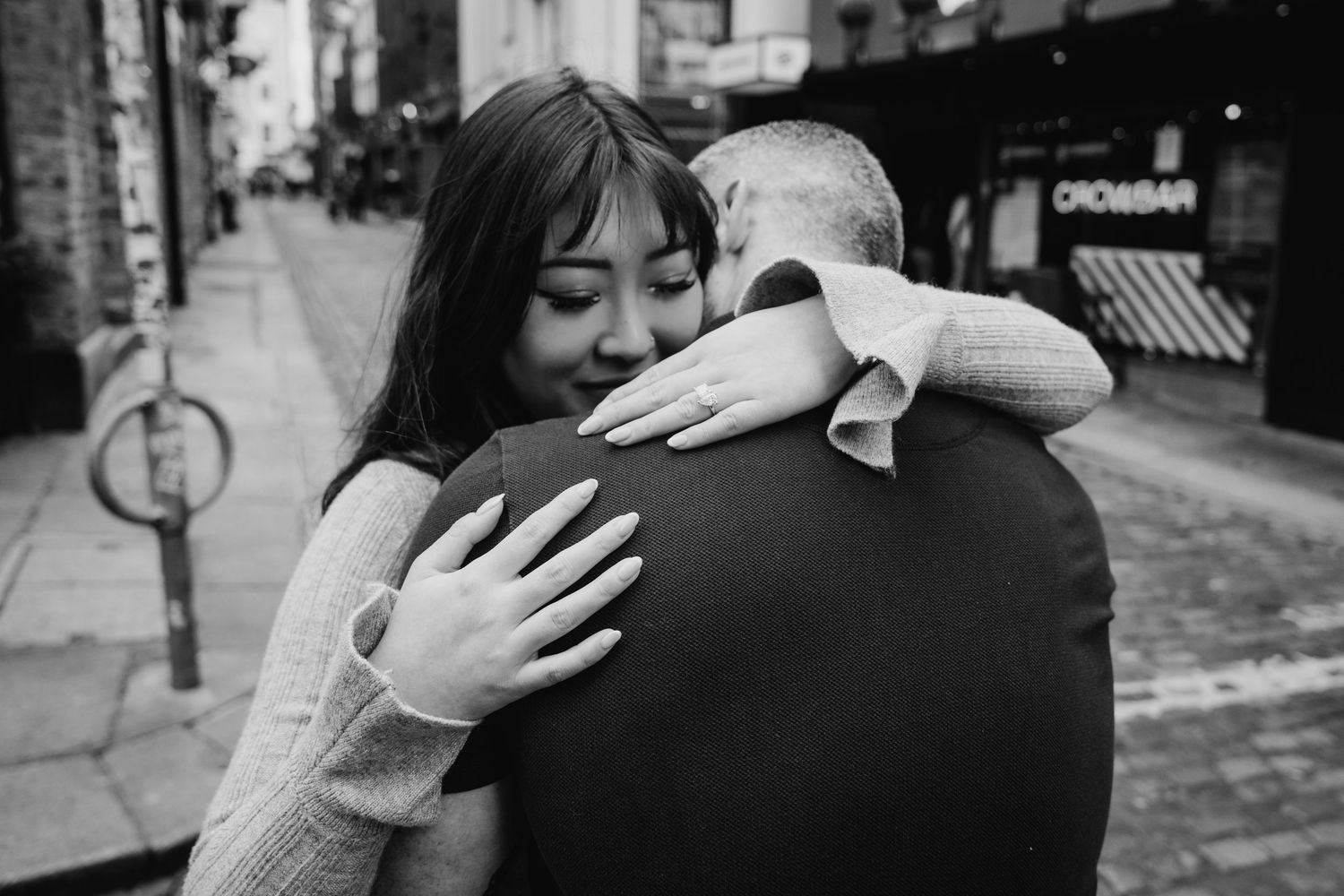 A tender embrace between two people on a city street captured in black and white photography. PHOTOGRAPHER Dublin ireland