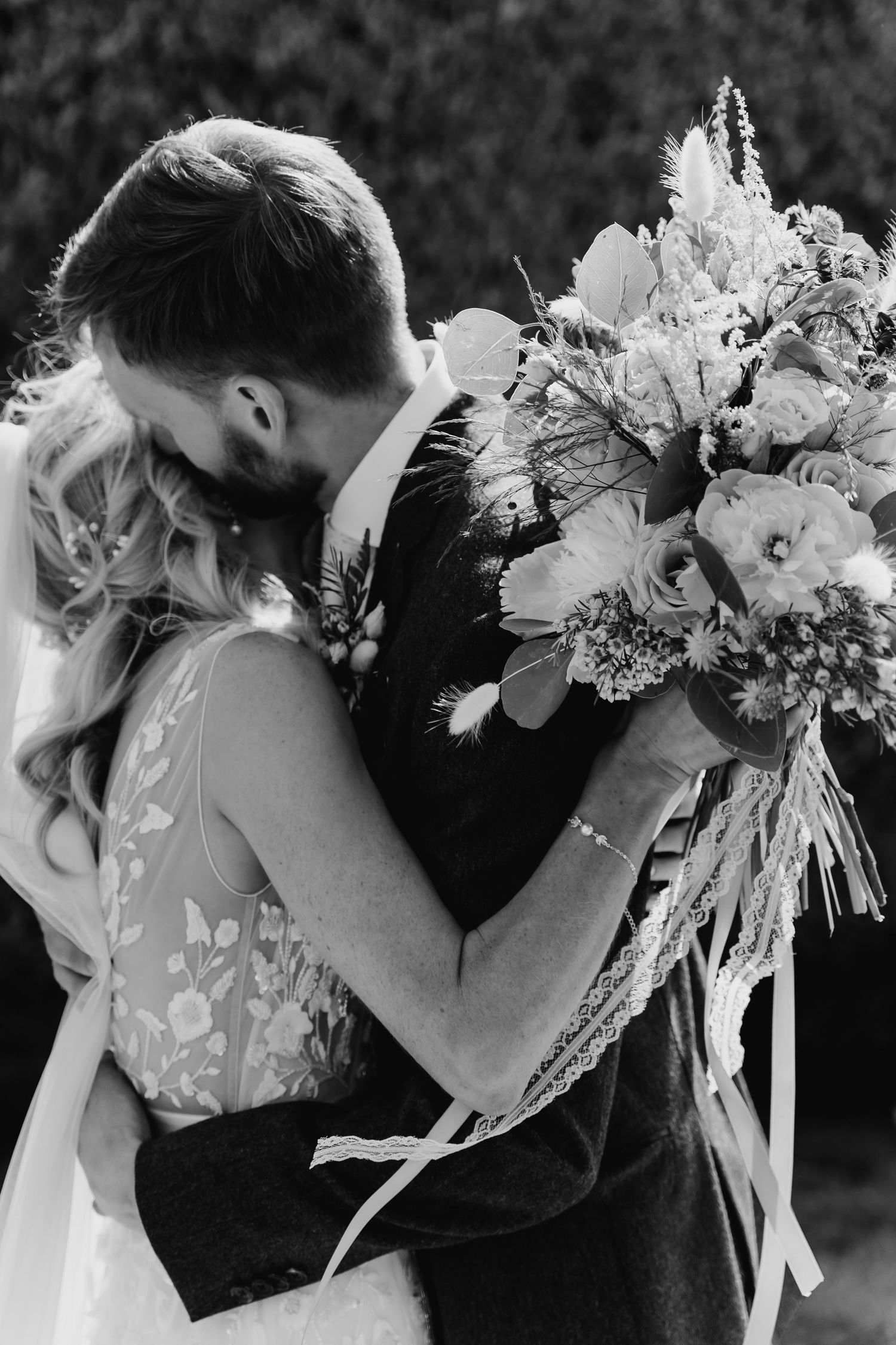 A romantic black and white wedding moment with a couple embracing while holding a lush floral bouquet. Wedding PHOTOGRAPHER Dublin