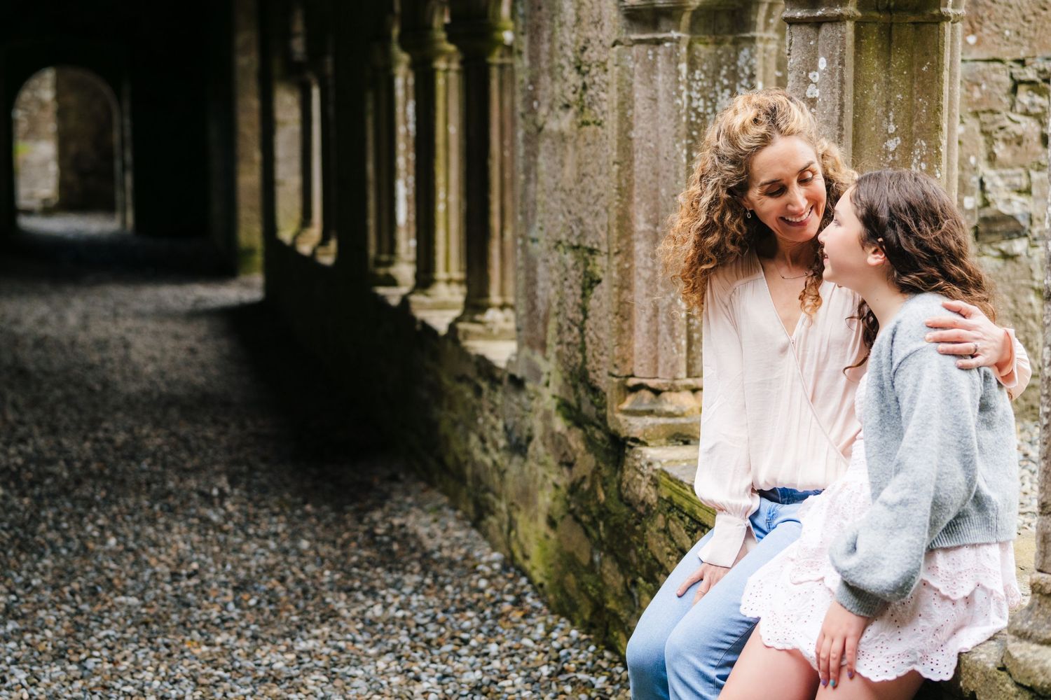 Candid moments captured of family interacting in stone corridor of historic ruins. BEctive abbey family photographer dublin