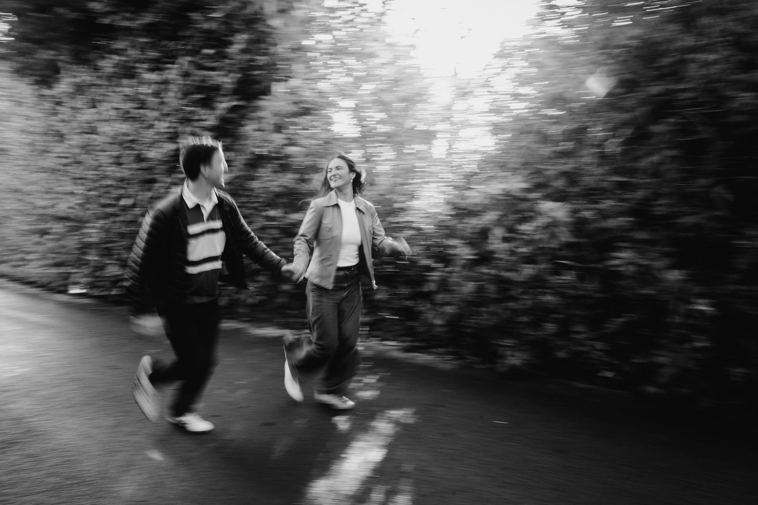 Two people hold hands and dance together on a path in a black and white romantic scene. engagement photographer dublin