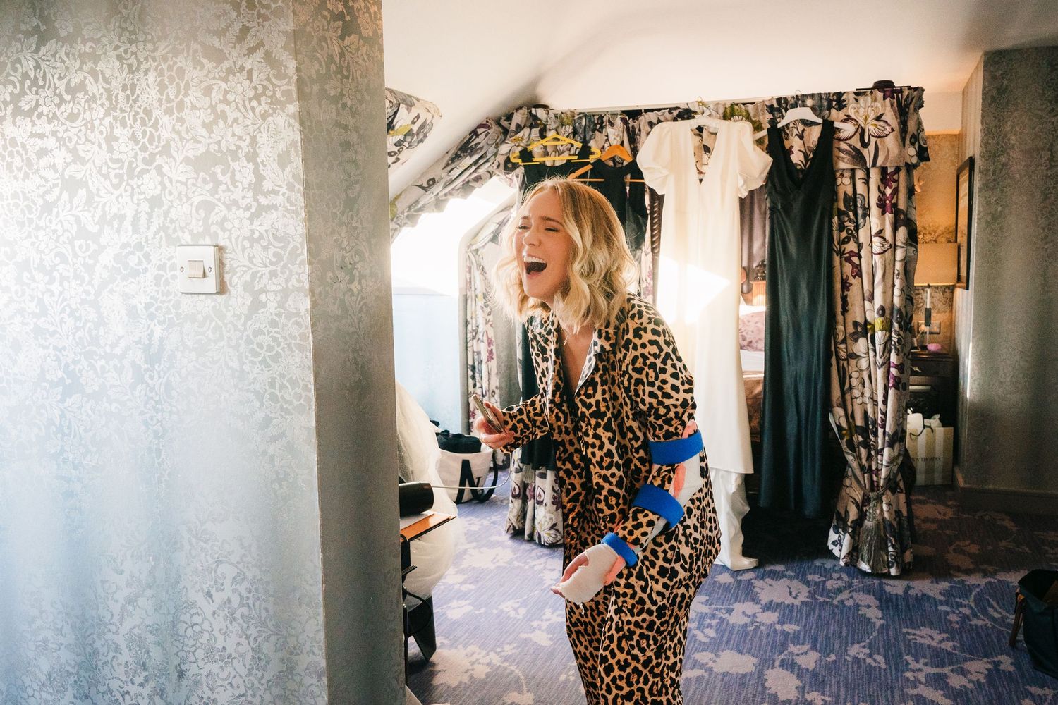 Fashion model in leopard print dress poses against white textured wall in elegant hallway setting. Wedding photographer dublin