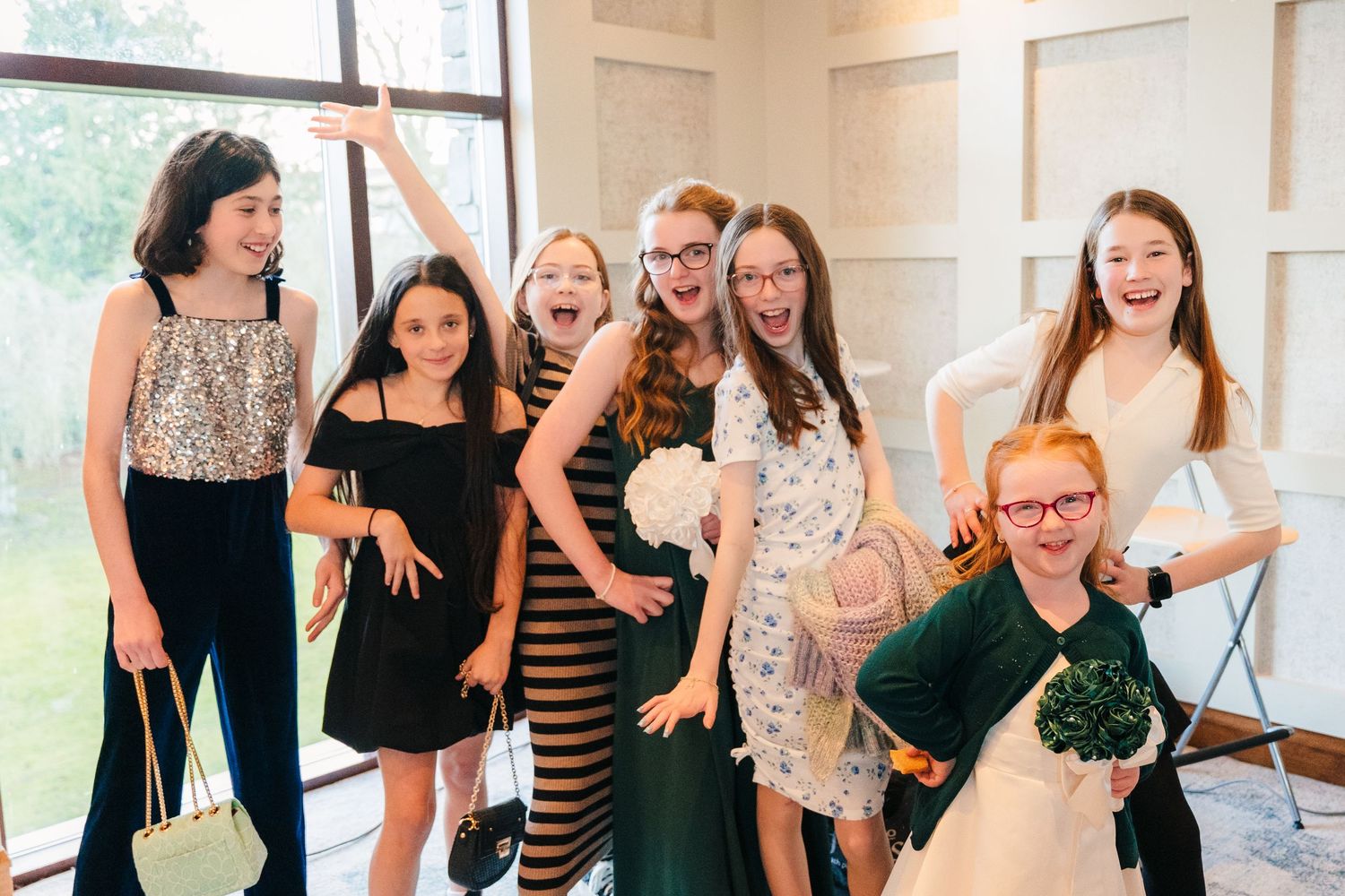 Group of wedding guests laughing and posing together indoors by large windows.  Wedding PHOTOGRAPHER Trim Castle