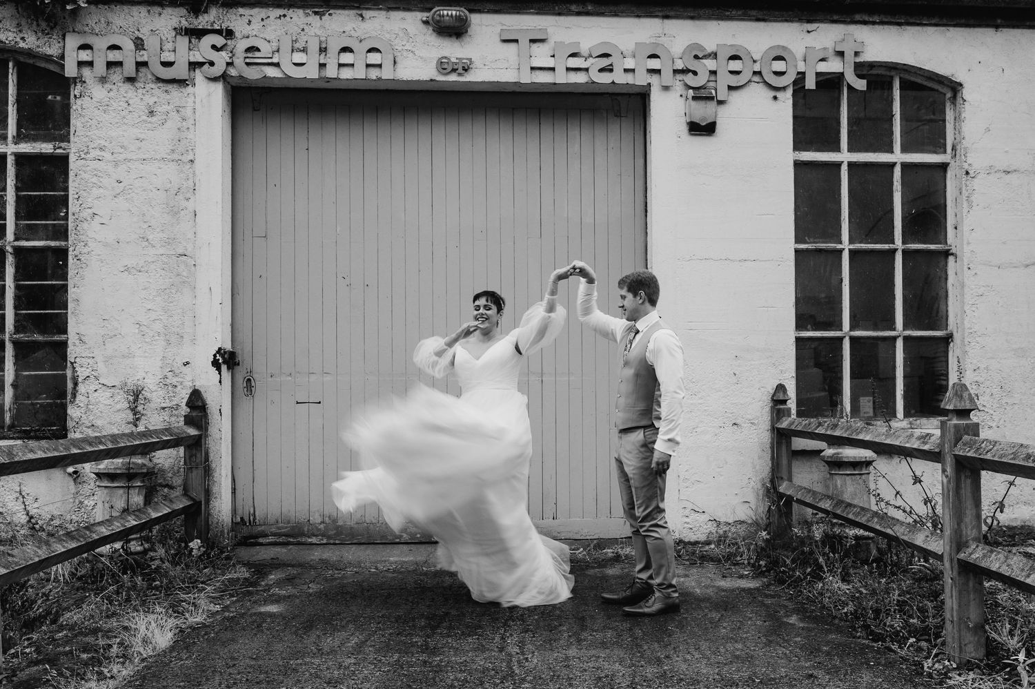 Millhouse slane wedding photographer dublin Black and white photo of bride twirling dress in front of rustic garage door.
