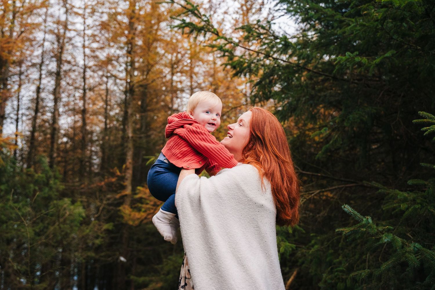 Family Photographer Dublin Ireland A family shares tender moments among autumn trees during a forest photoshoot.