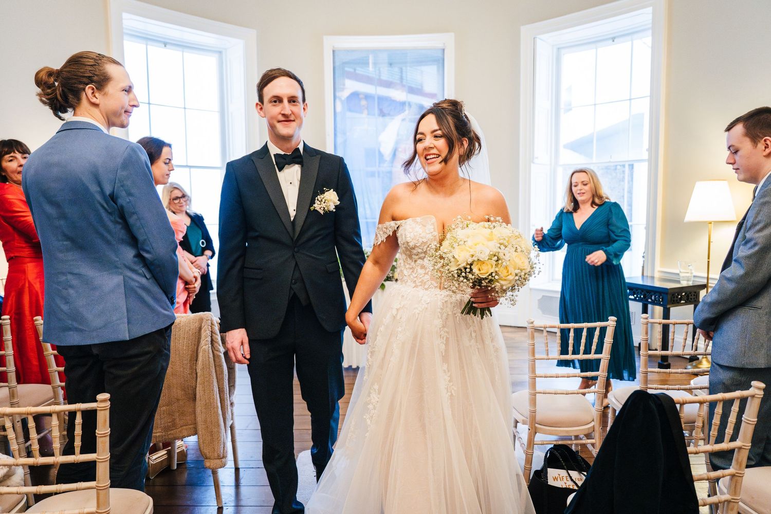 Wedding celebration in bright room with guests watching ceremony proceedings. Wedding PHOTOGRAPHER Dublin