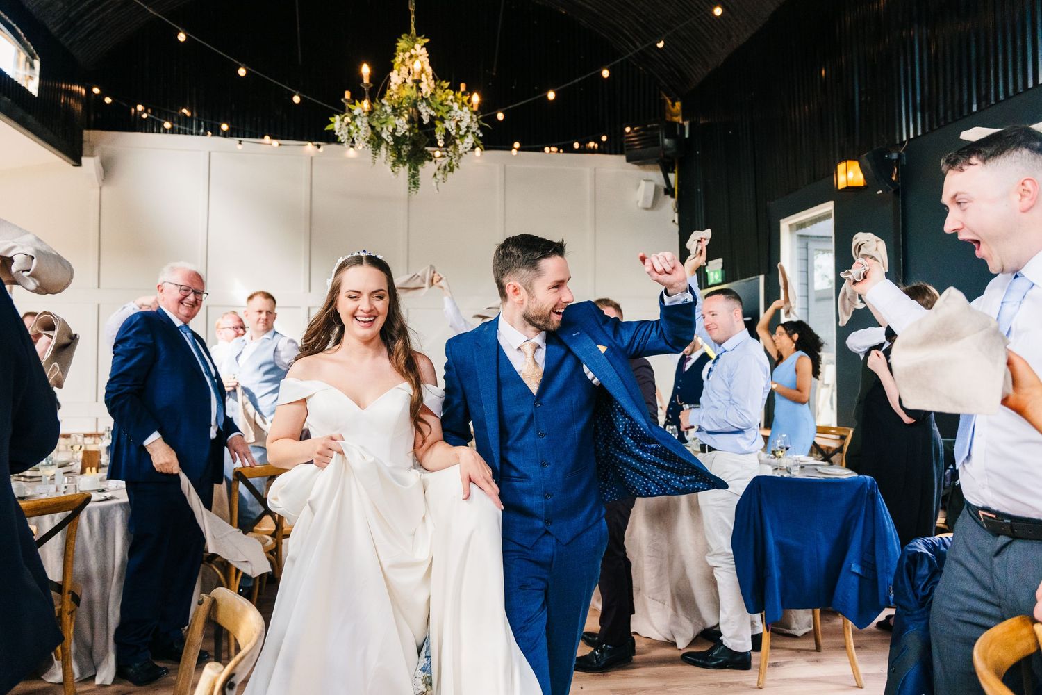 Poulaphouca Wedding photogNewlyweds make their grand entrance into an elegant reception venue decorated with chandeliers and twinkle lights.