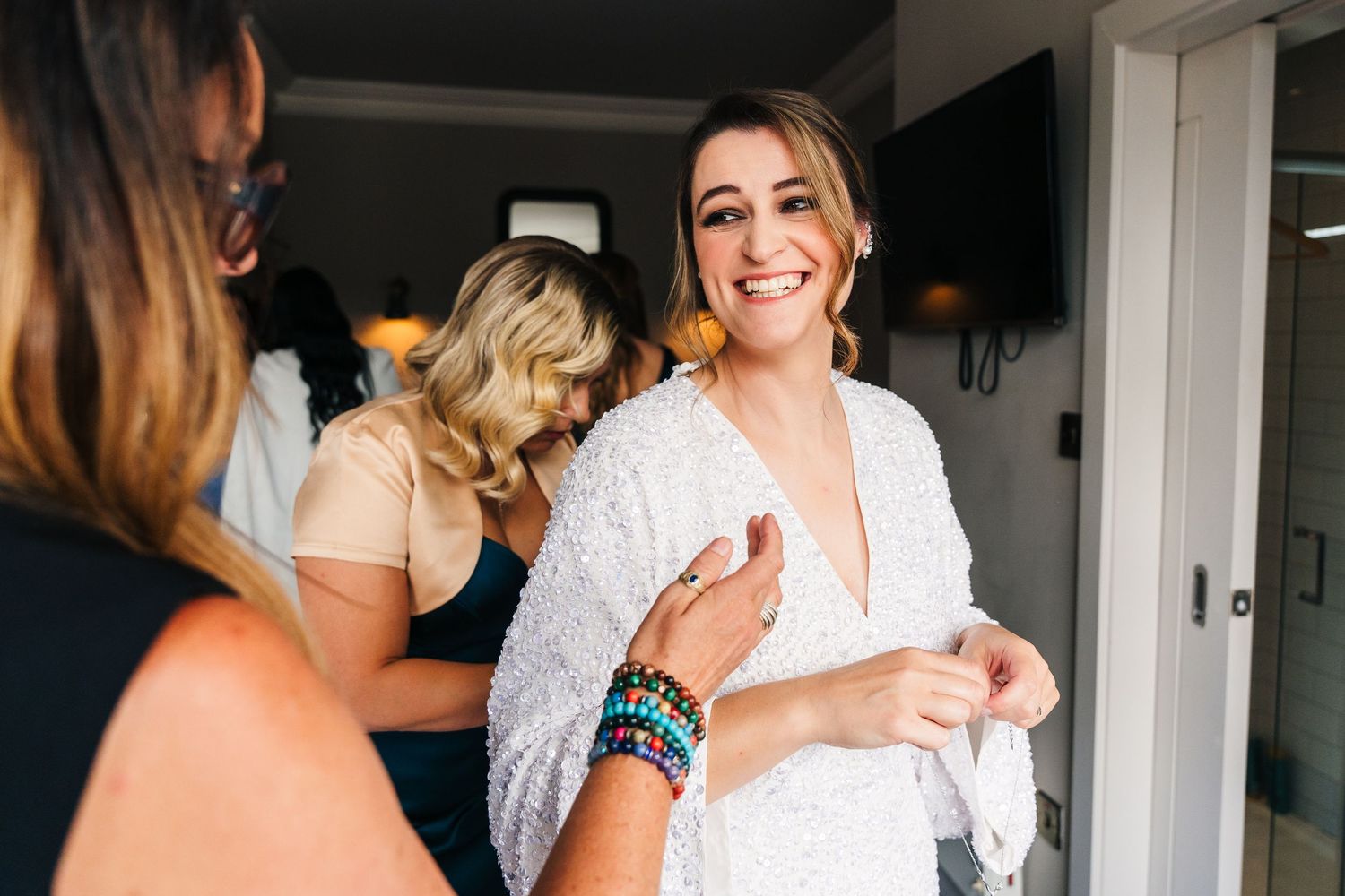Someone in a white robe getting ready with others during wedding preparations. House Dublin Wedding Photographer