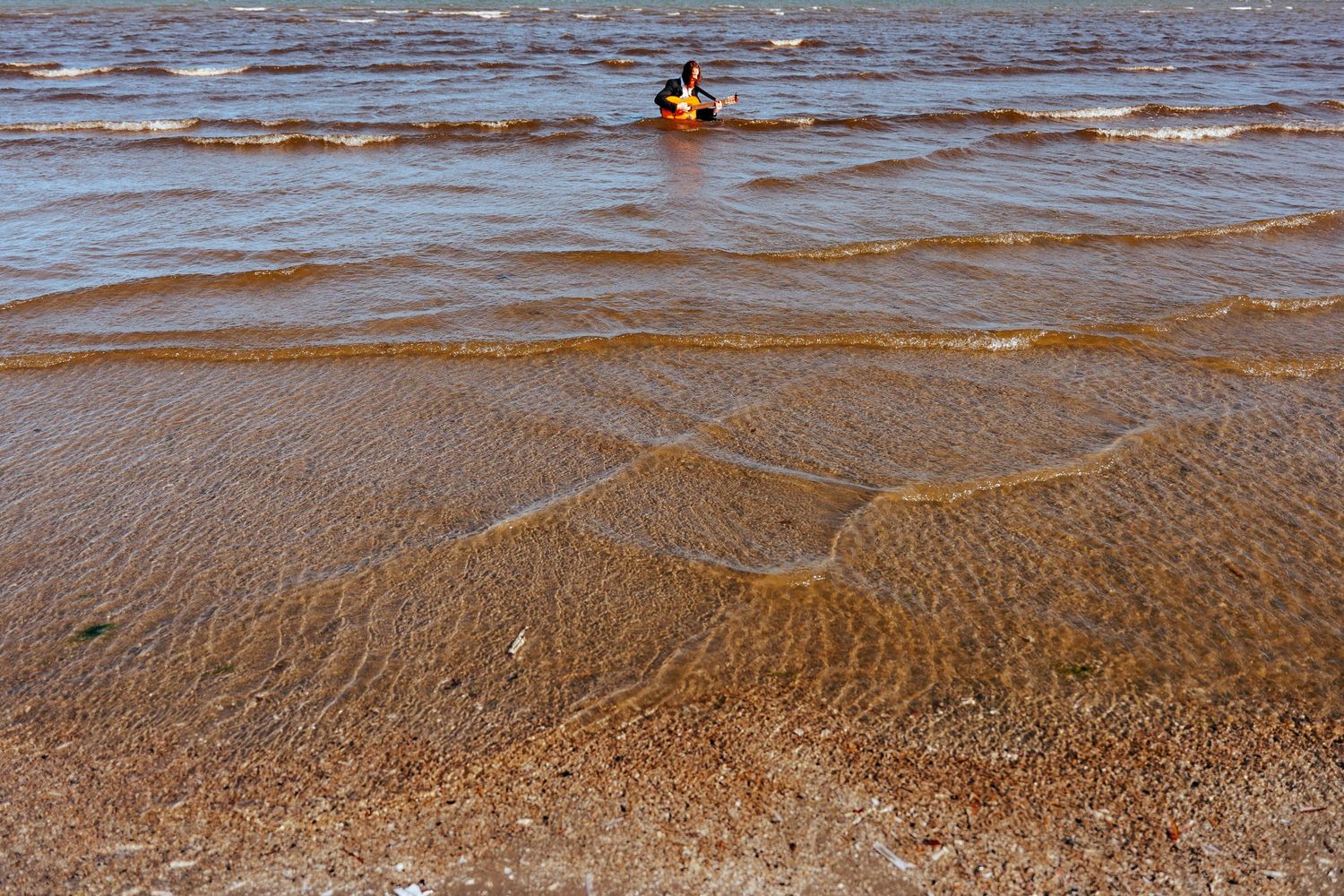 Brown water rippling over sandy beach during low tide with small waves creating natural patterns. PHOTOGRAPHER Dublin