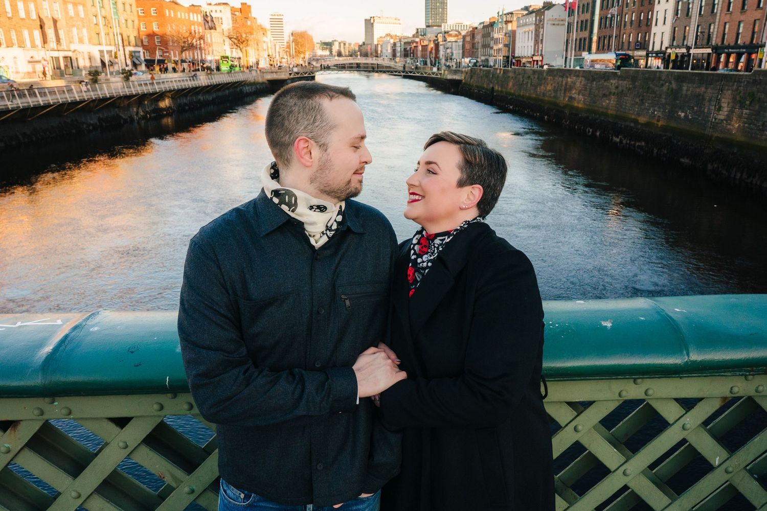 Two people share an intimate moment along a canal in Dublin at sunset with historic buildings in the background.