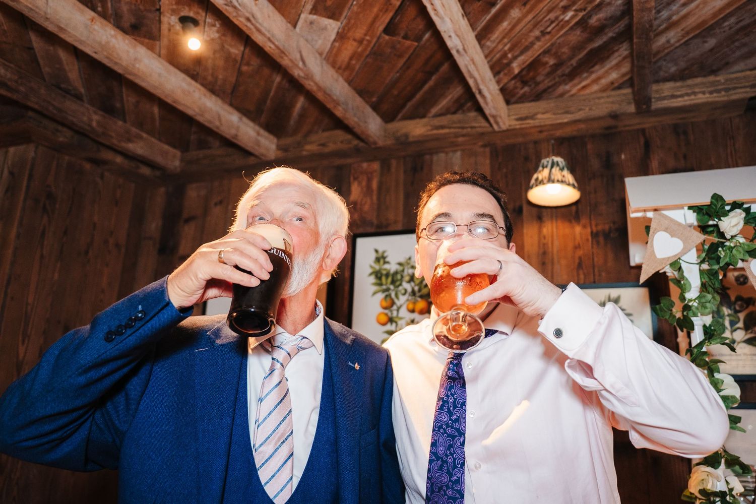 Wedding reception inside rustic wooden barn with guests sharing drinks and laughter. The Dean Dublin Wedding Photographer