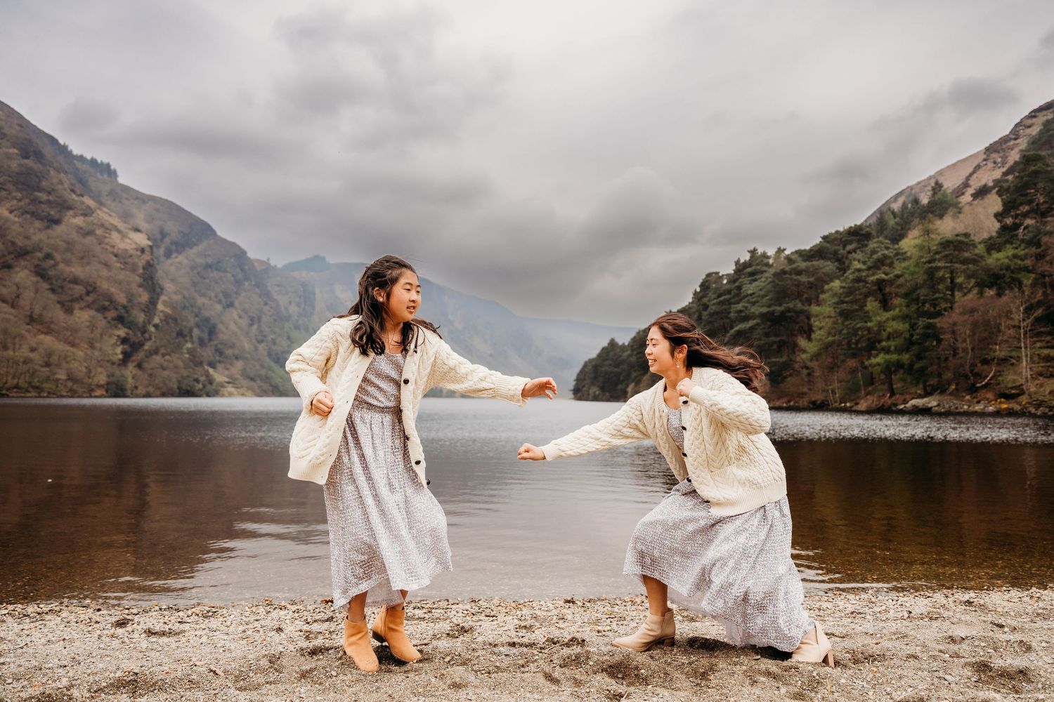 Two people in elegant white outfits pose for photos near a misty mountain lake while exploring the scenic landscape. family PHOTOGRAPHER Dub