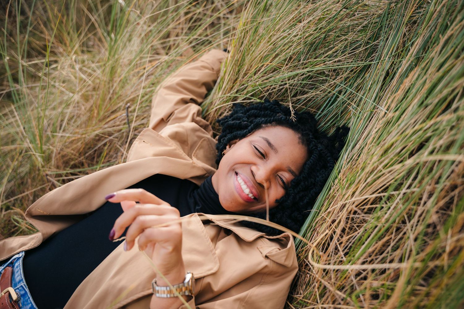 Candid moments captured of person lying in coastal grass wearing tan coat. Dublin professional headshots photographer