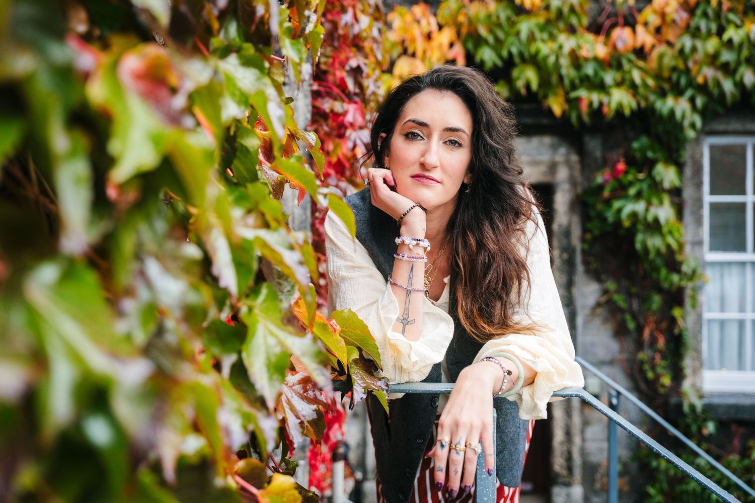 People enjoying a fall photoshoot among colorful autumn leaves and trees near a historic building. professional headshots dublin photographe