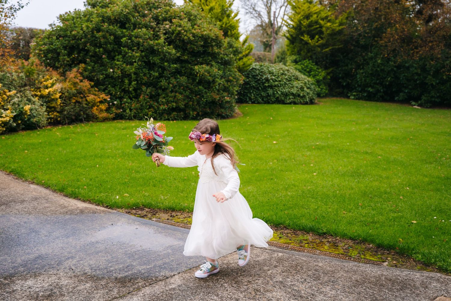 A white wedding dress flows gracefully across a green lawn on an autumn day.