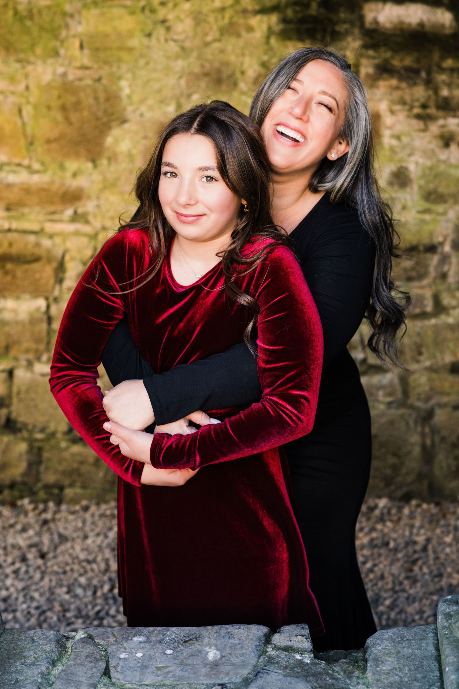 Sequential photos showing embracing figures, one wearing a deep red velvet top against a stone wall. Family PHOTOGRAPHER Dublin