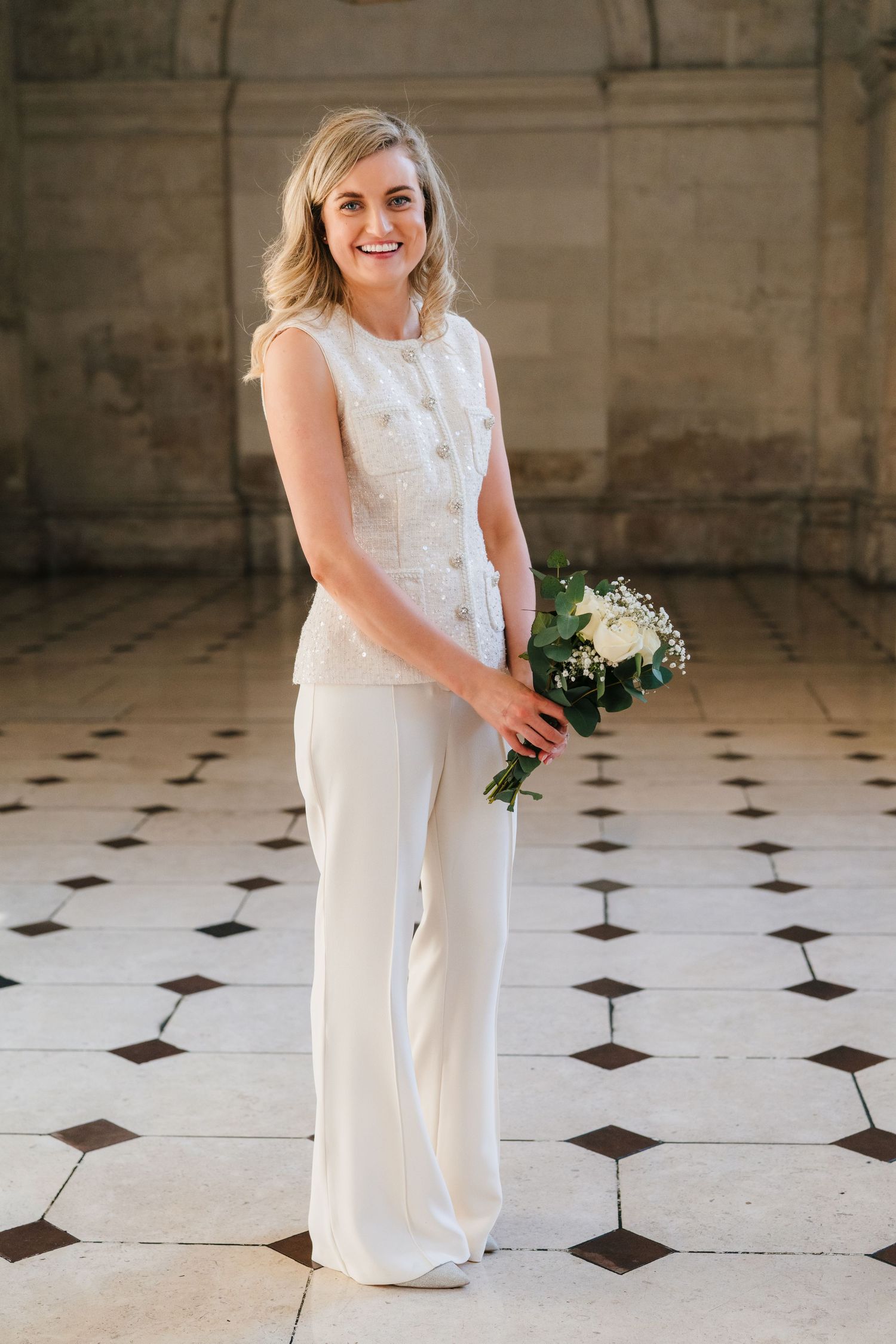 Person in white outfit poses on checkered floor in historic building interior. City Hall Dublin wedding photogrAPher