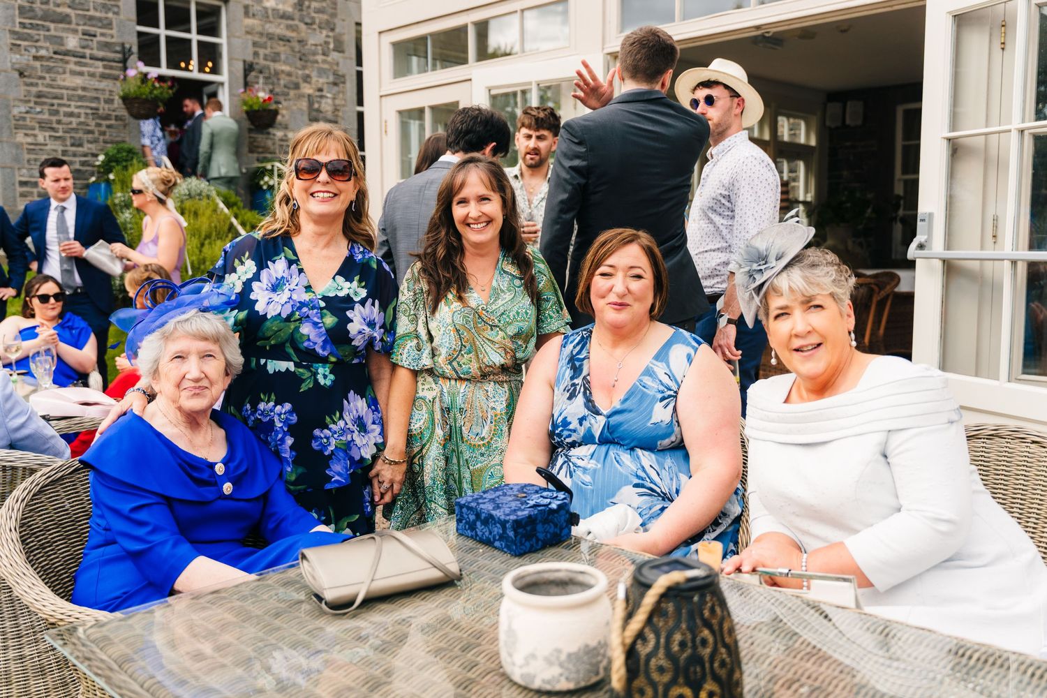 Millhouse slane wedding photographer dublin Group enjoying outdoor gathering on stone patio with white building facade in background.
