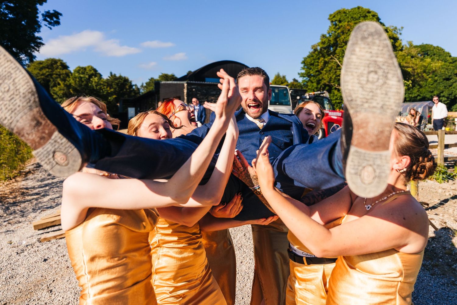 Poulaphouca Wedding photographer wicklow  Groomsmen playfully lift groom horizontally for fun wedding photo outdoors.