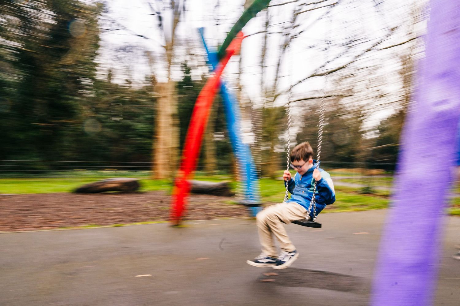 Family photographer Dublin Ireland  Motion-blurred action shot of someone swinging on colorful playground equipment.