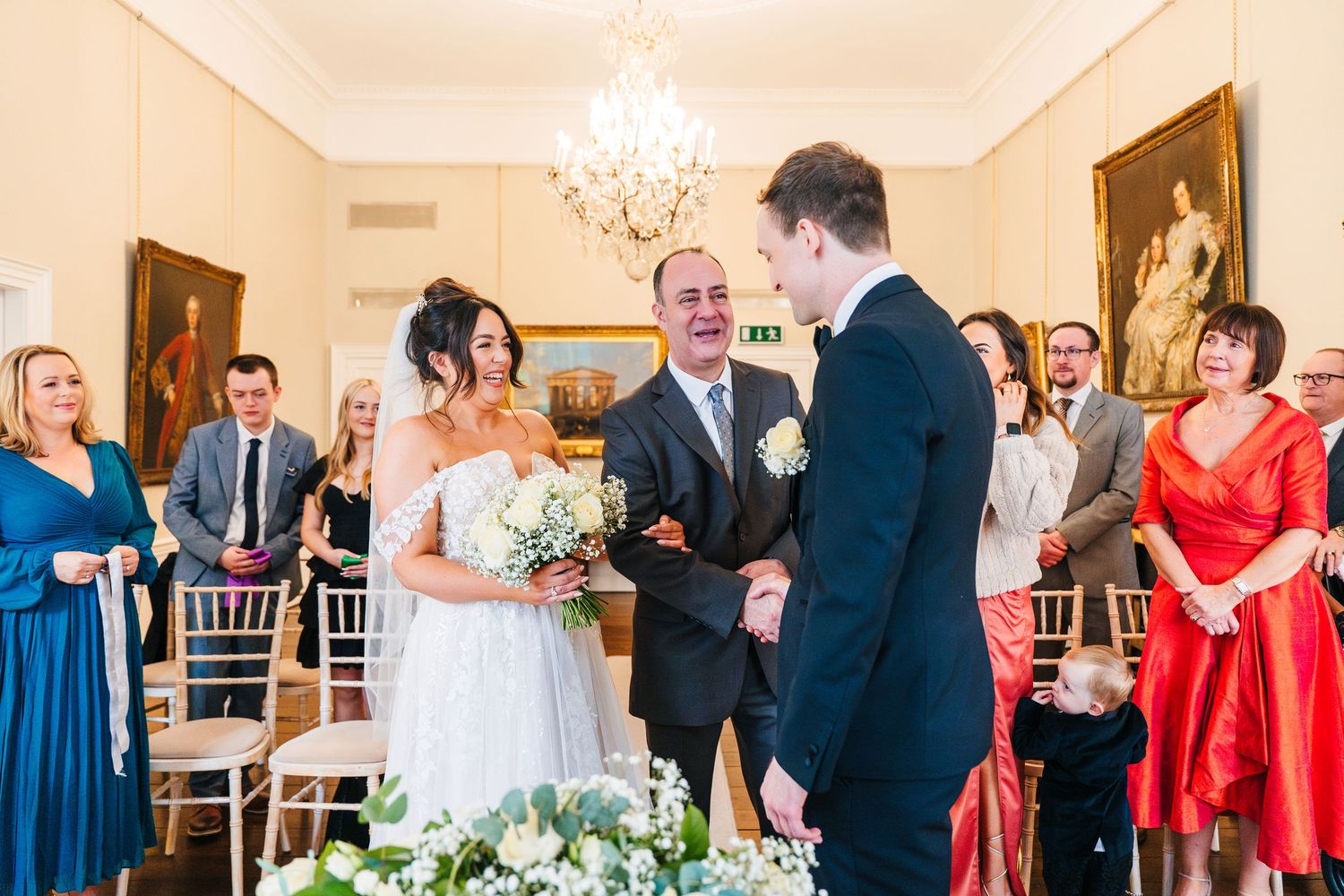 Group of wedding guests enjoying themselves at an elegant reception with warm lighting and formal attire.  Wedding PHOTOGRAPHER Dublin