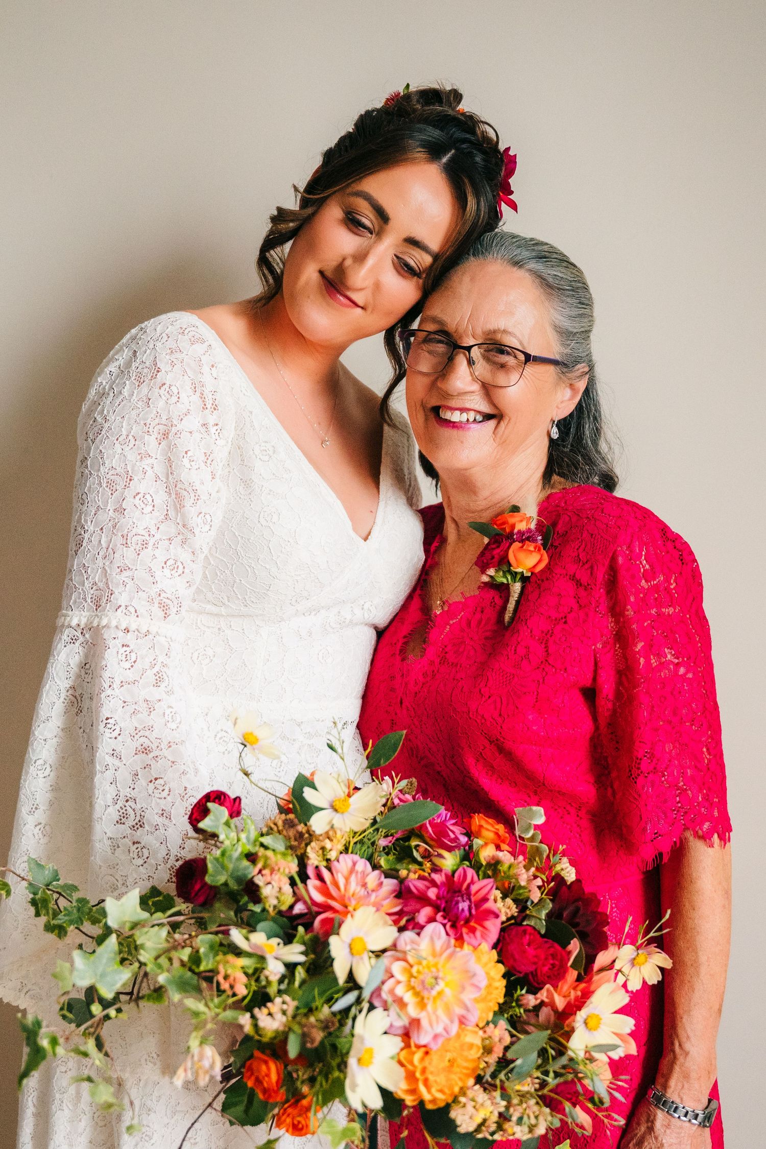 Elegant white lace wedding dress and vibrant red ensemble showcased with colorful floral bouquet in studio portrait. Wedding Photography Tri