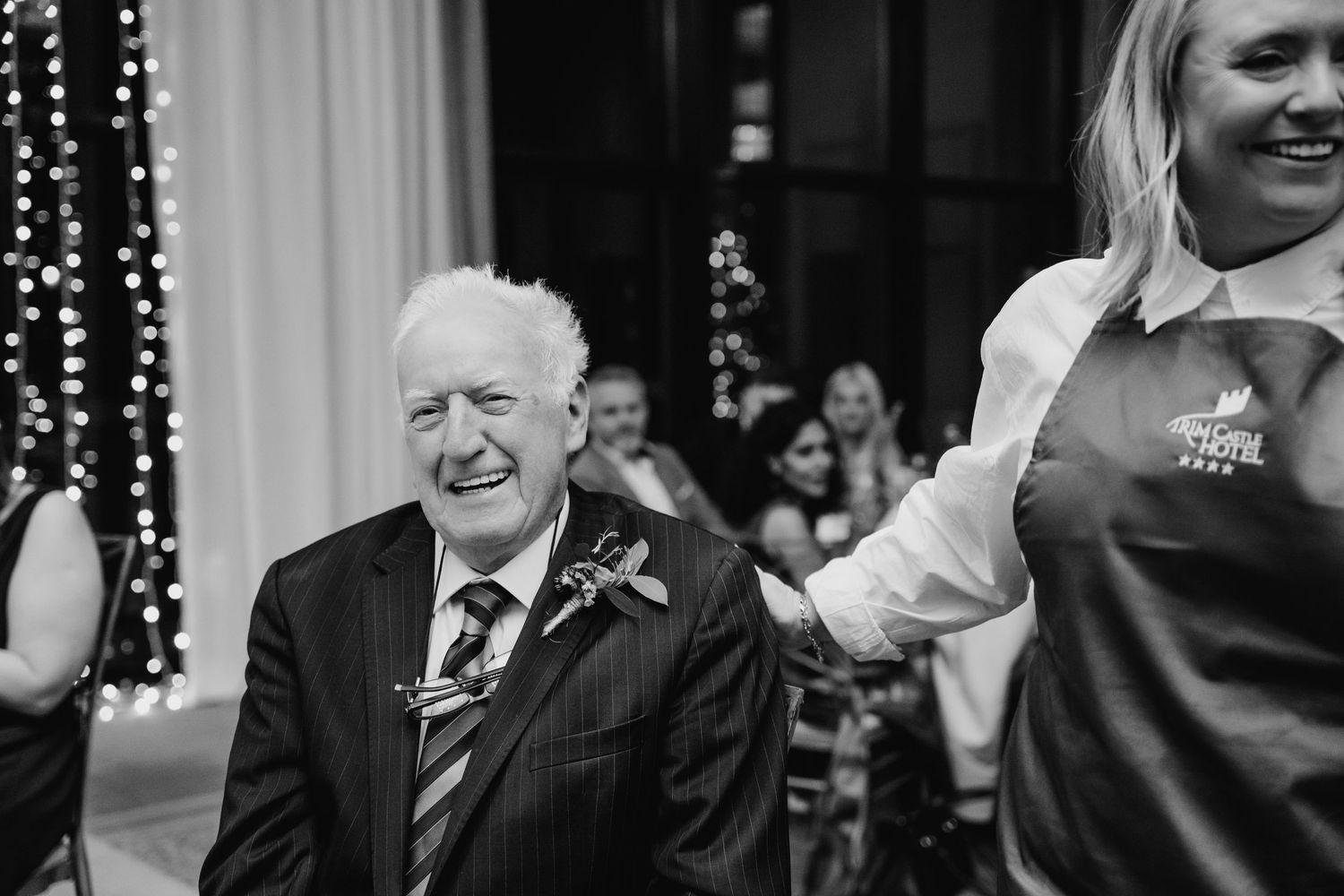 Wedding reception guests laughing and celebrating with string lights in the background.Wedding Photography Trim Castle Ireland