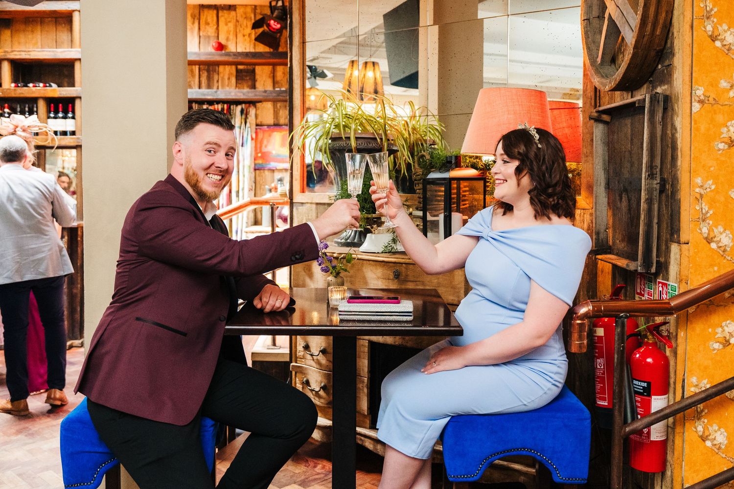 A couple shares a joyful moment while seated at a rustic wooden table with decor. House Dublin Wedding Photographer