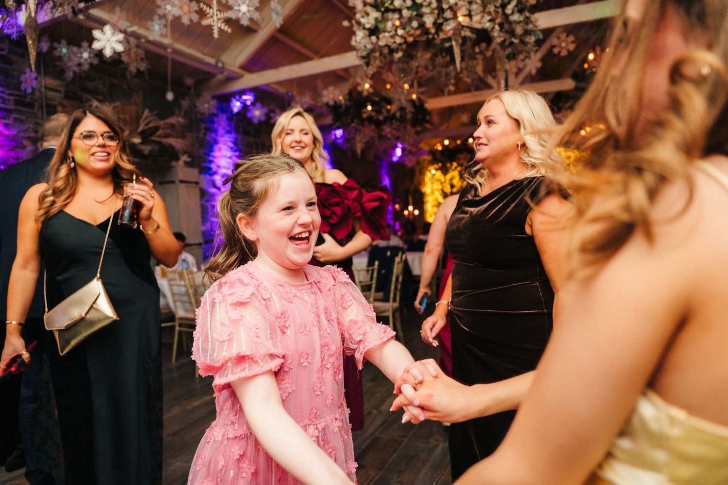 Wedding guests dance and celebrate at reception with colorful lighting and snowflake decorations. Ballymagarvey Wedding photographer