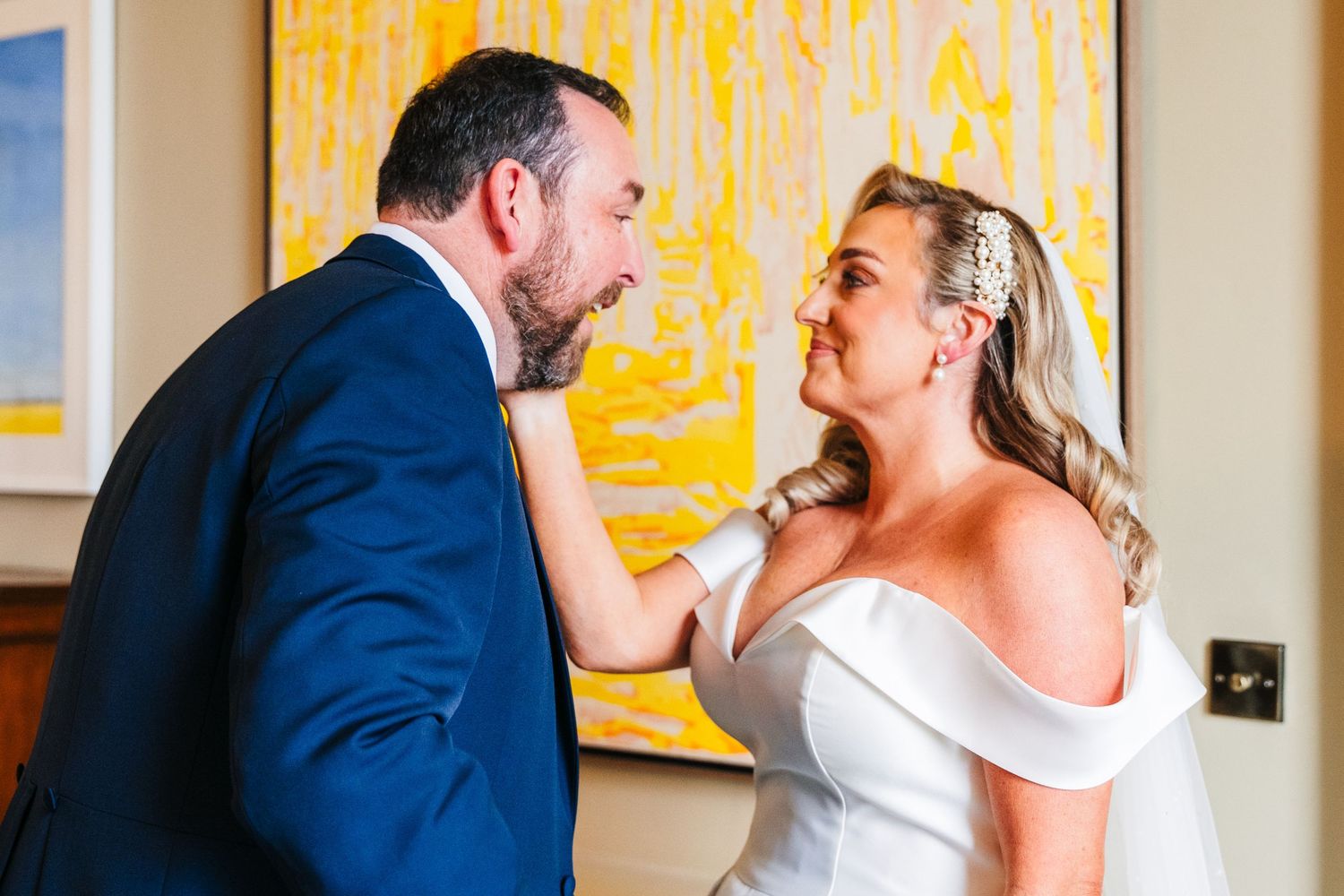 Couple sharing an intimate moment in front of a bright yellow abstract painting. Virginia Park Lodge Wedding Photographer Dublin Meath Irela