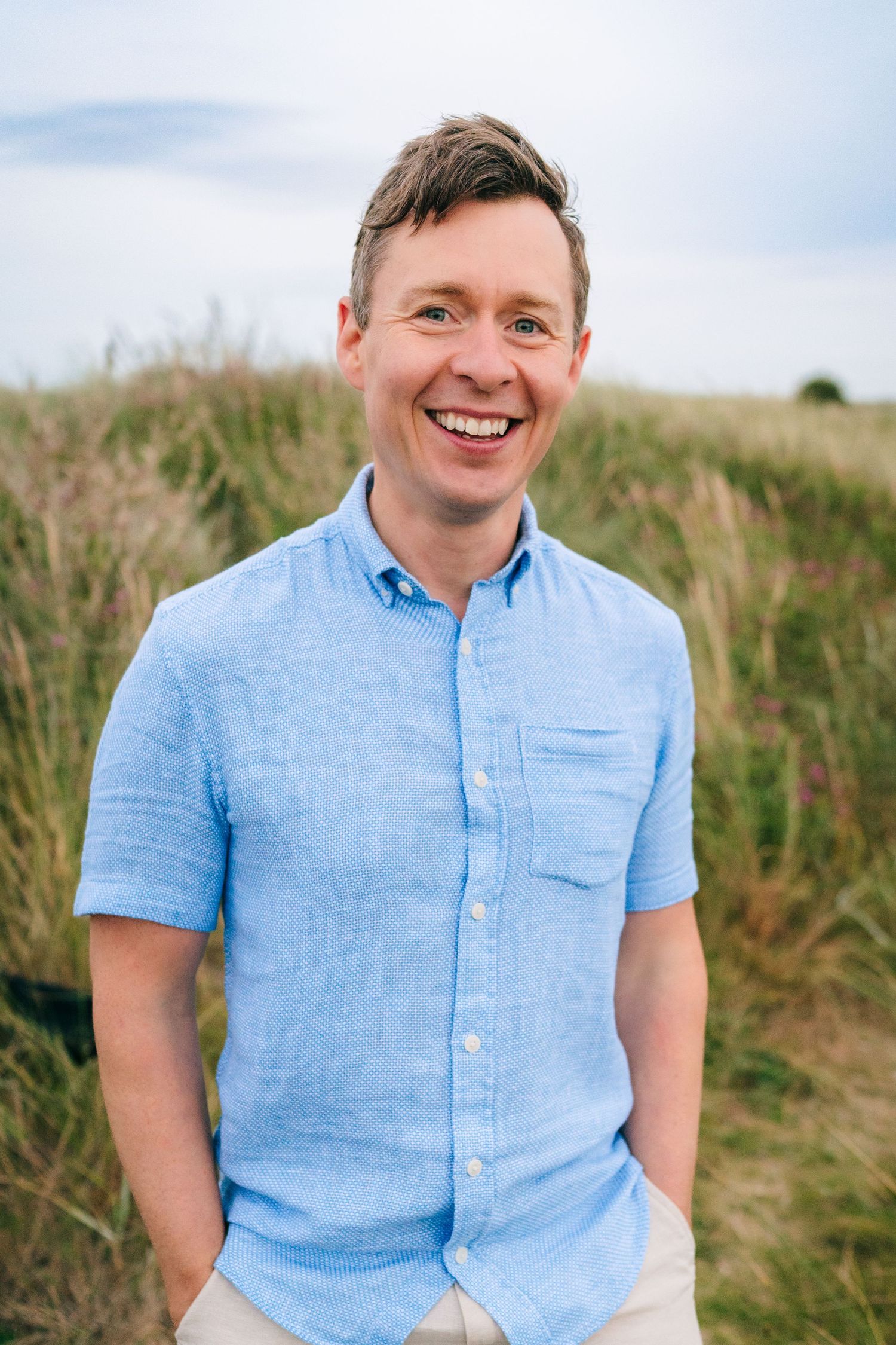 Casual outdoor portraits in a light blue shirt against coastal scenery.  Family photographer Dublin Ireland