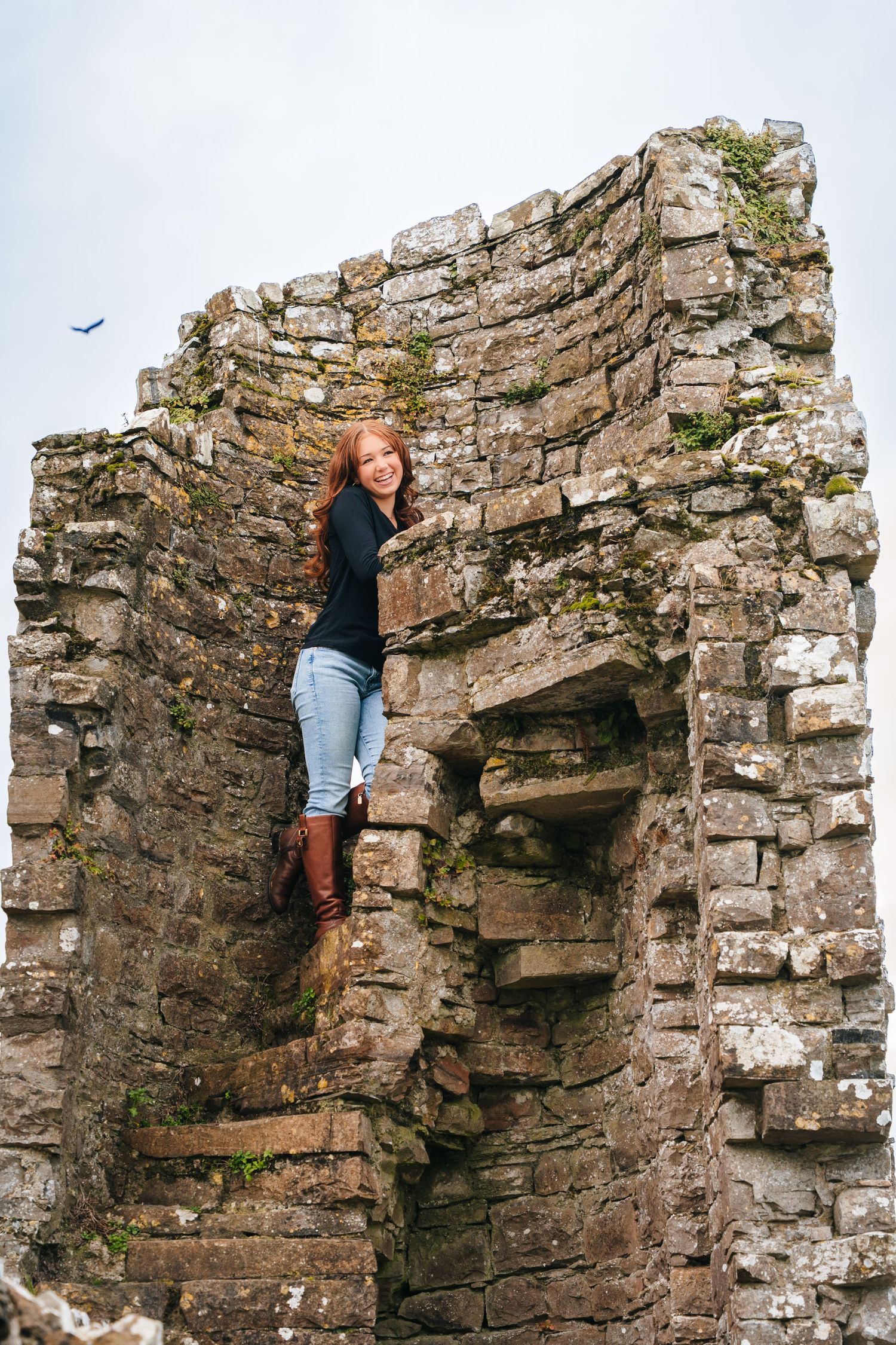 Person climbing ancient stone ruins and weathered castle walls. BEctive abbey family photographer dublin
