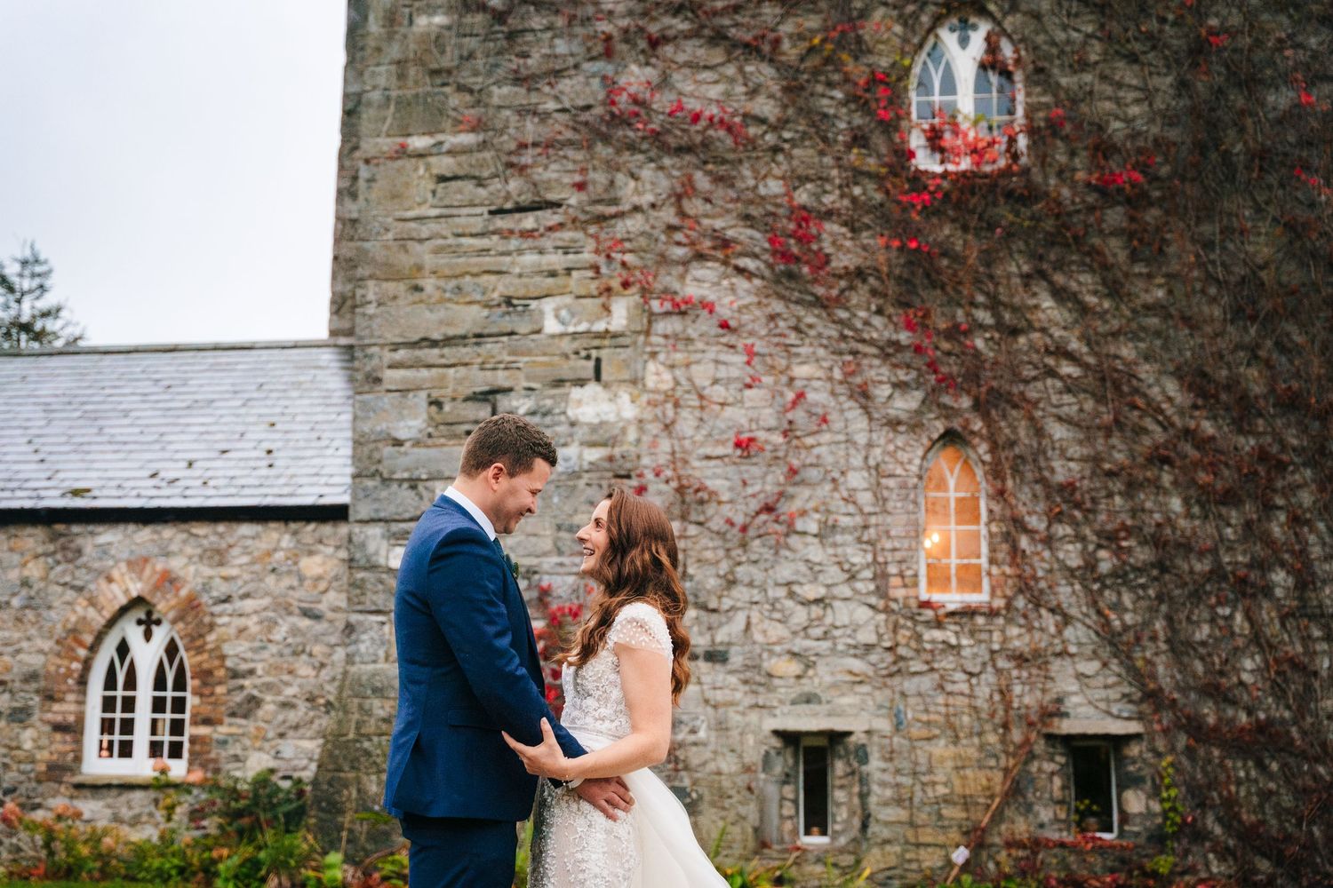 Stone church exterior with climbing red vines creates romantic wedding backdrop.
