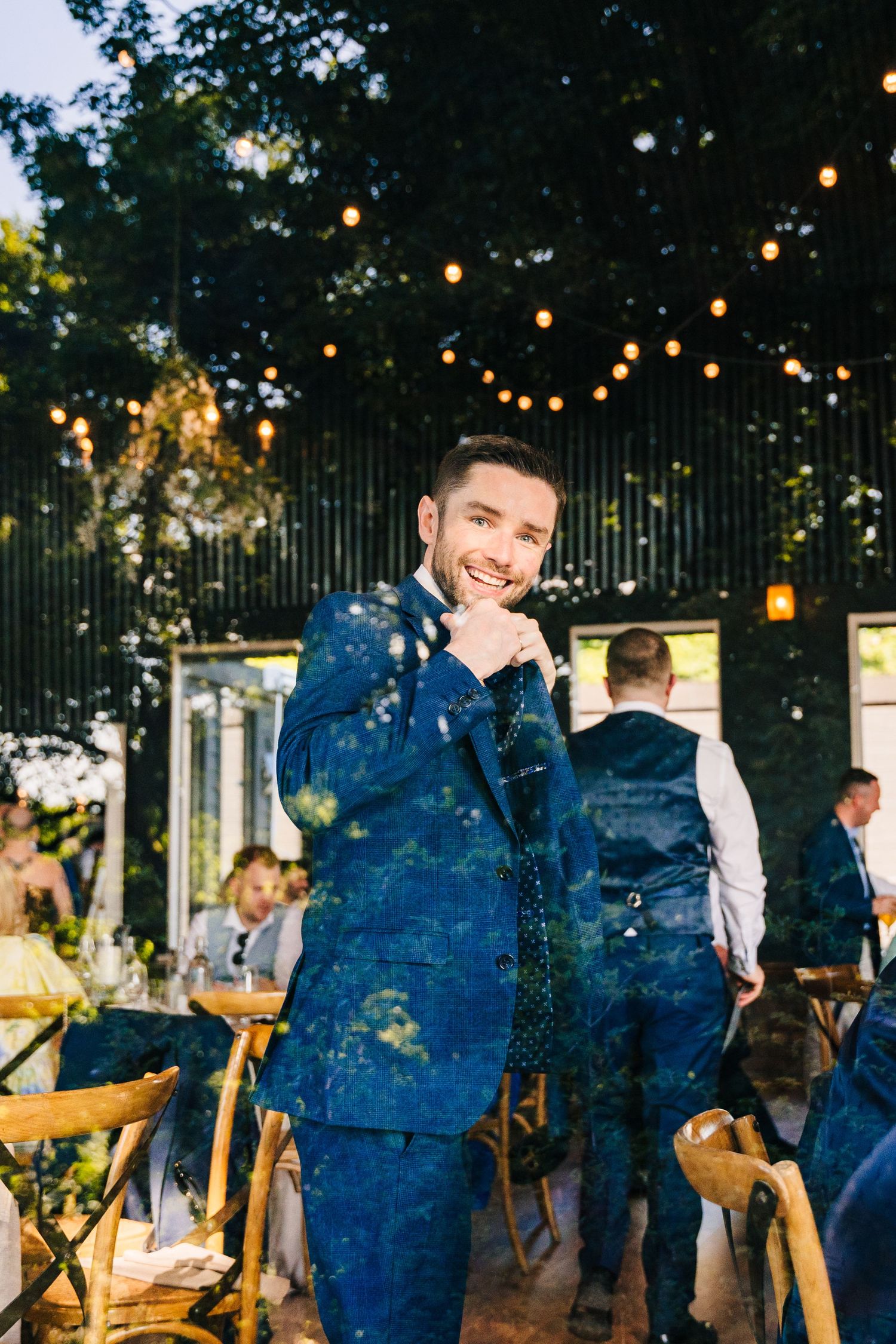 Poulaphouca Wedding photographer wicklow  Evening outdoor wedding reception with string lights glowing above wooden tables and chairs.