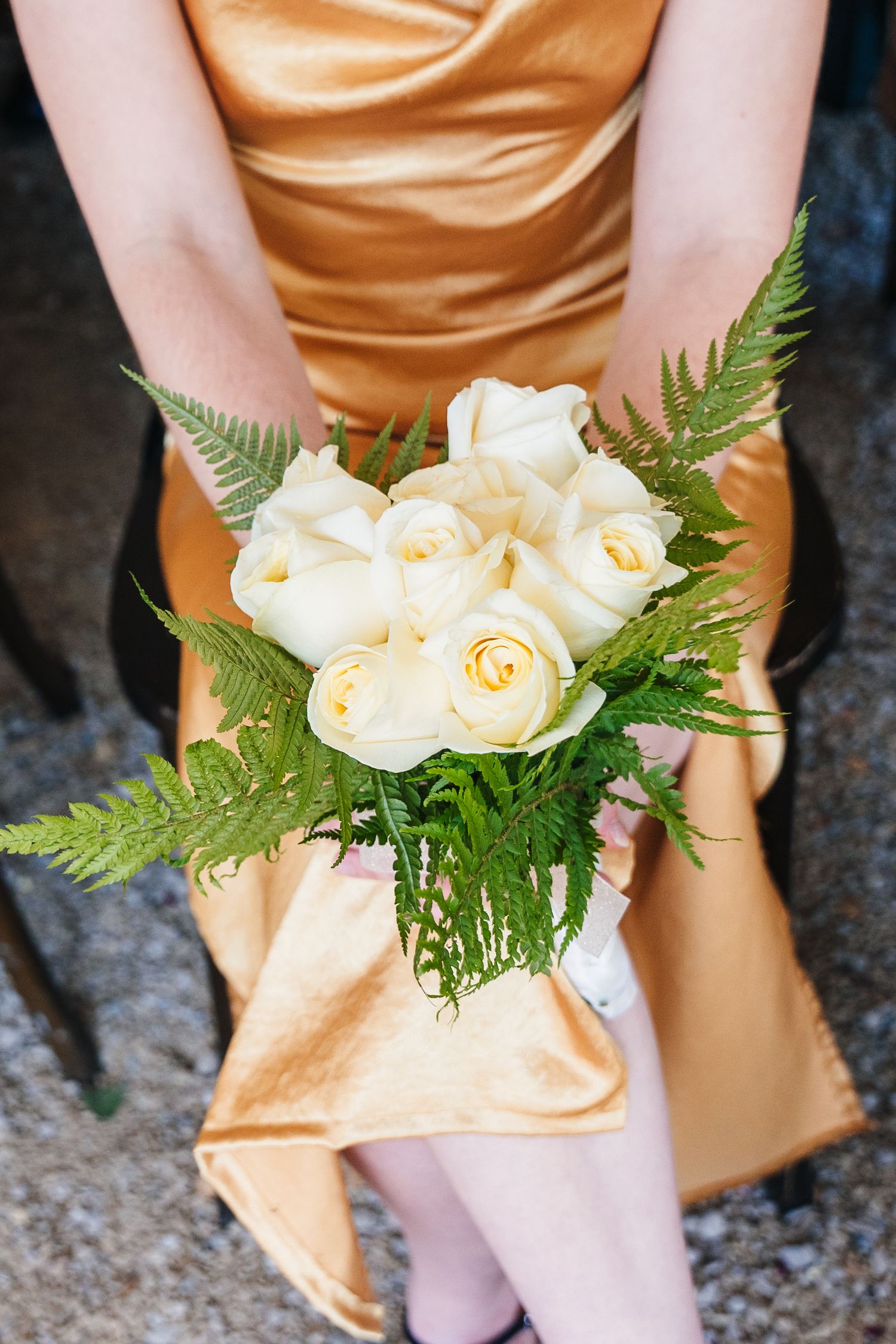 Poulaphouca Wedding photographer wicklow  A woman in a peach satin dress holds a classic cream rose and fern bouquet.