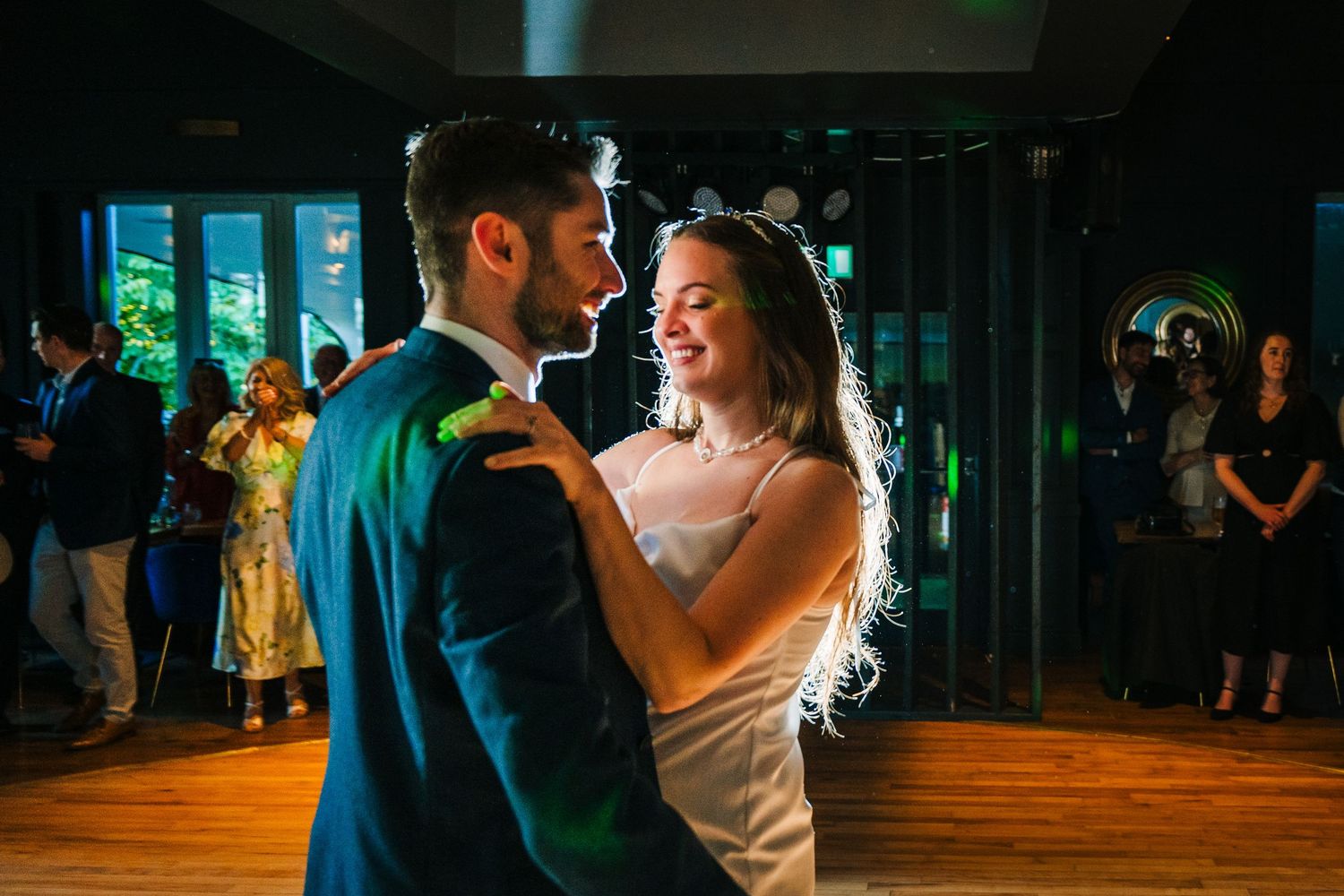 Poulaphouca Wedding photographeA romantic first dance moment captured in a dimly lit reception venue with guests watching in the background.