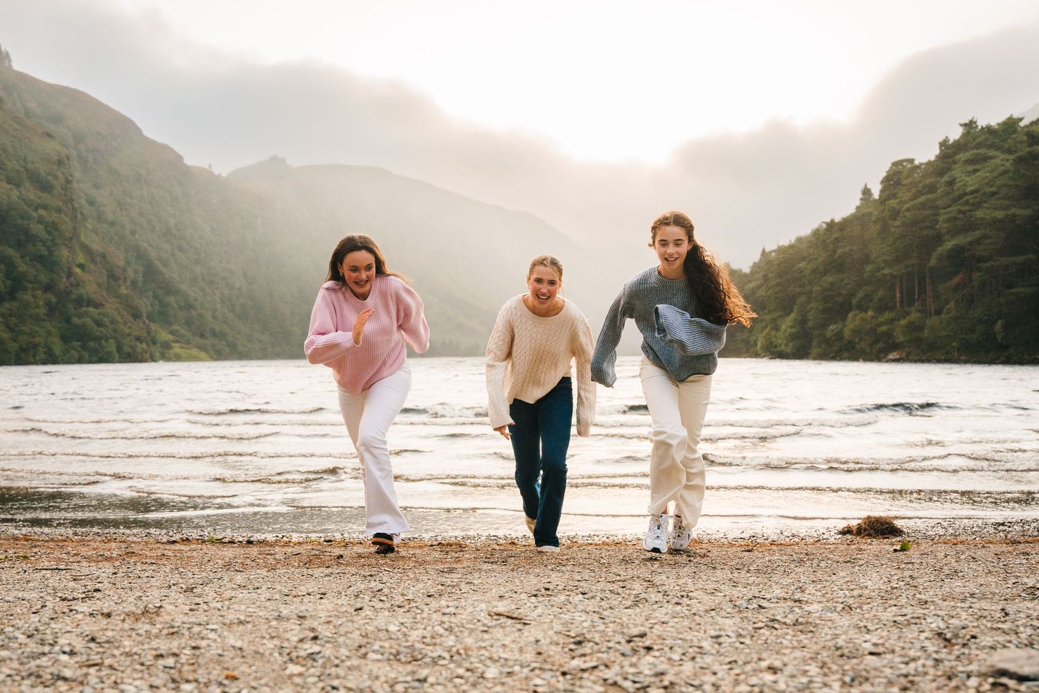 Family photographer Ireland Dublin Small group walking along a misty beach shoreline at sunset.
