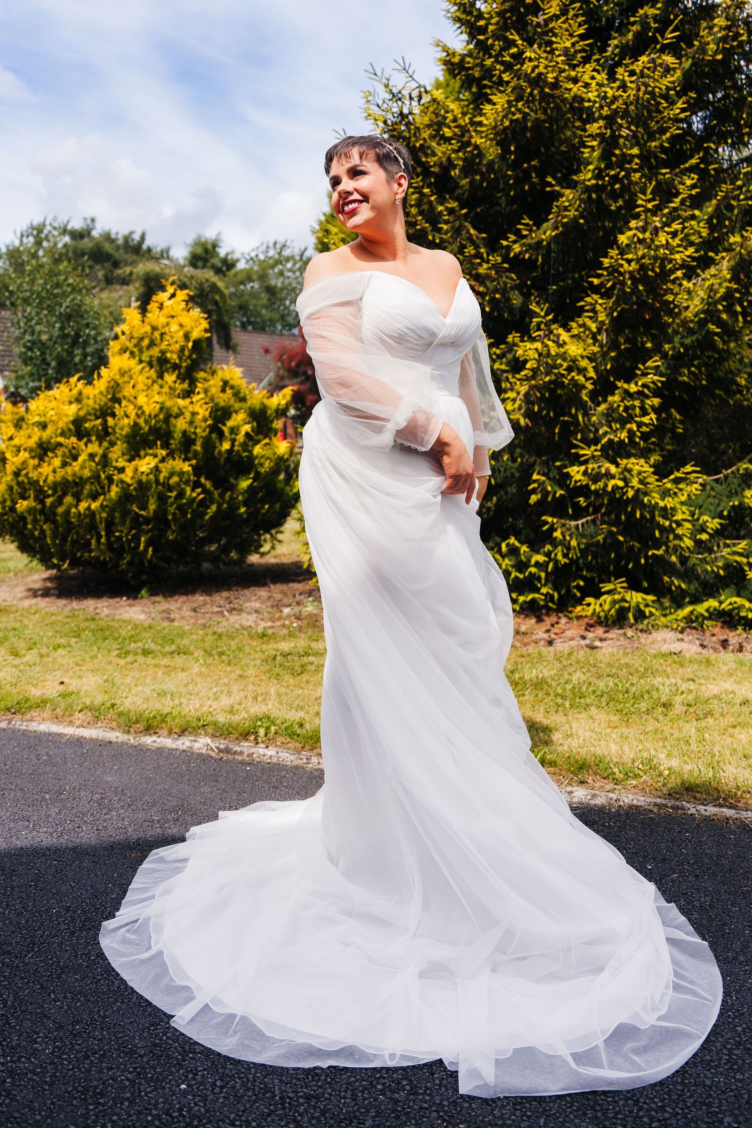 Millhouse slane wedding phA flowing white wedding dress swirls gracefully outdoors against a backdrop of bright yellow flowers and greenery.