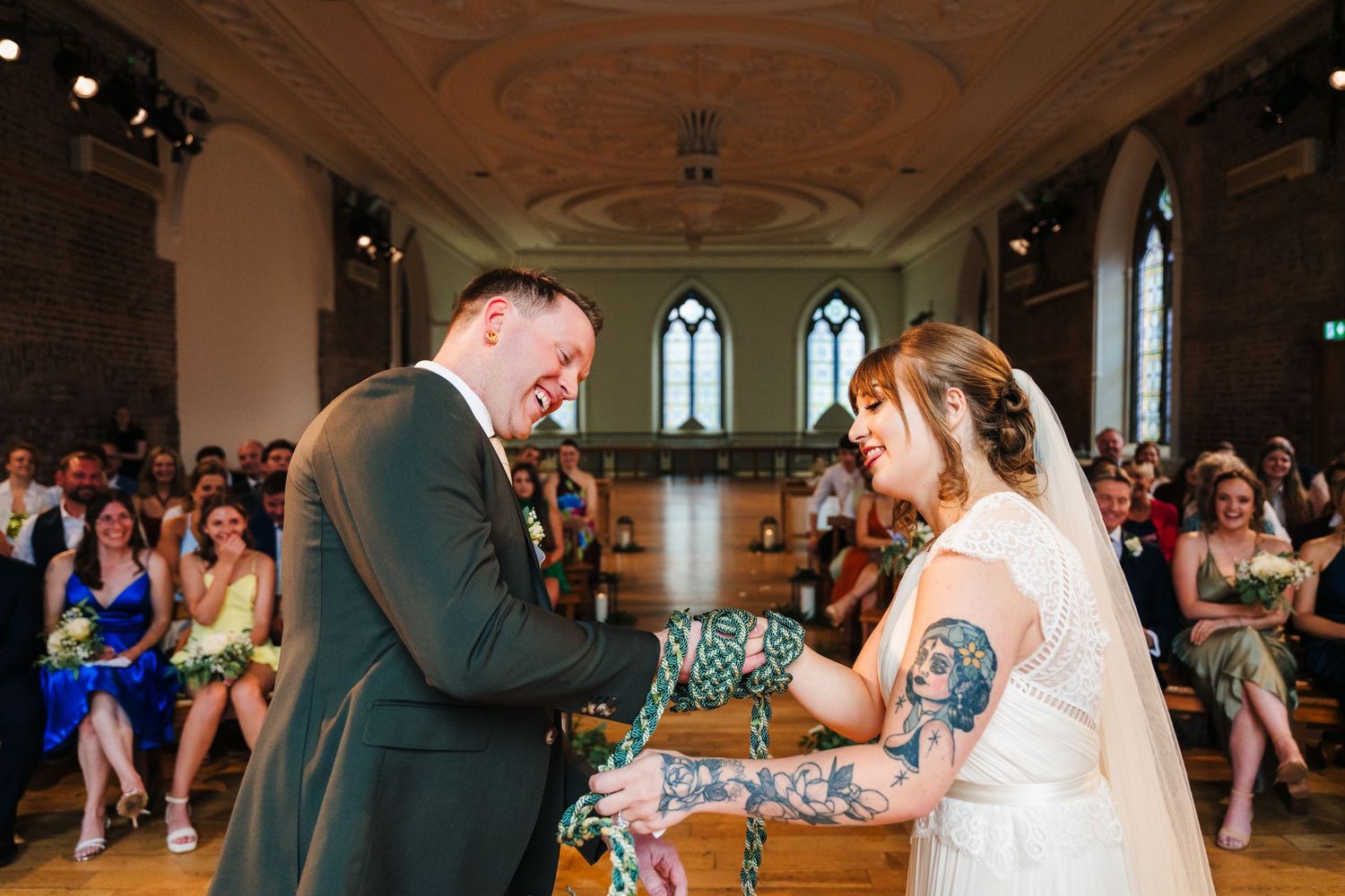 A wedding ceremony taking place in a historic venue with ornate ceiling and gothic windows. PHOTOGRAPHER Dublin Ireland Wedding