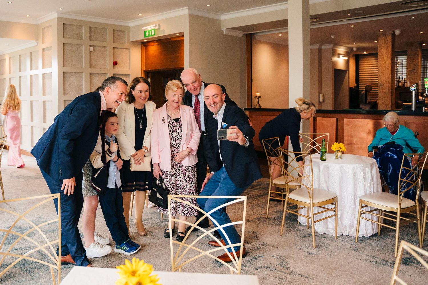 Wedding guests gather around tables during a celebration at an elegant indoor reception venue. Wedding Photography Trim Castle Ireland