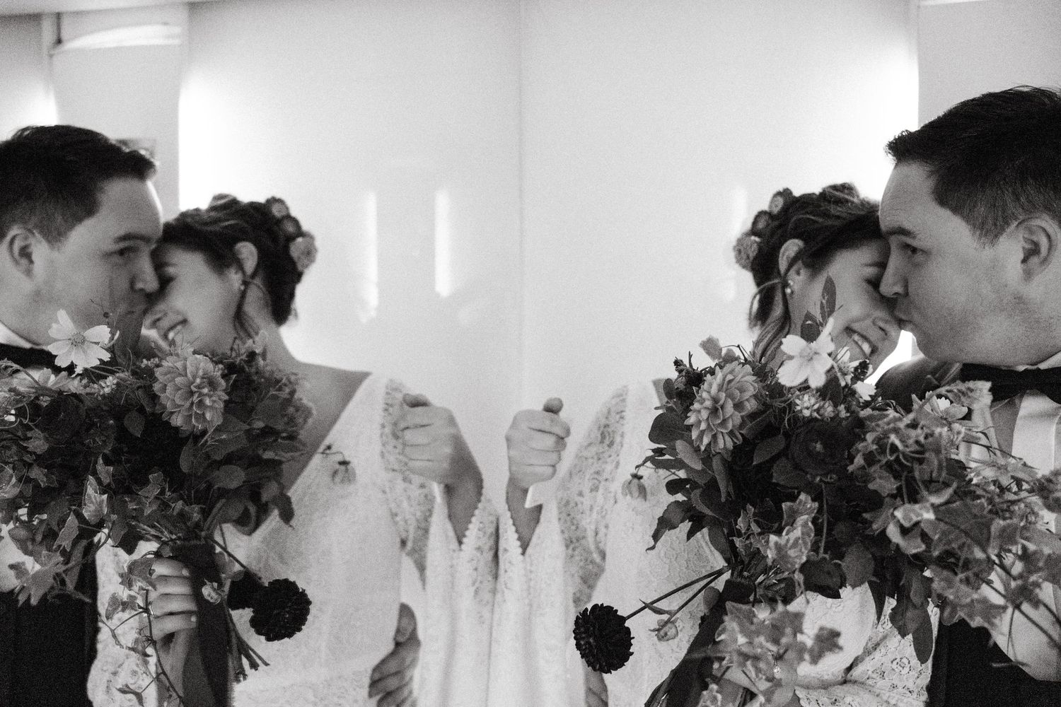 Wedding party holding bouquets poses together indoors against white backdrop.Wedding Photography Trim Castle Ireland