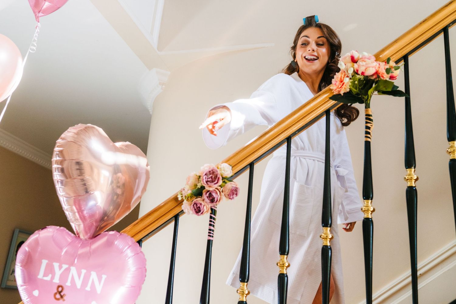 Castle Leslie Wedding Photographer party gathers around an elegant staircase decorated with pink balloons and flowers for celebration