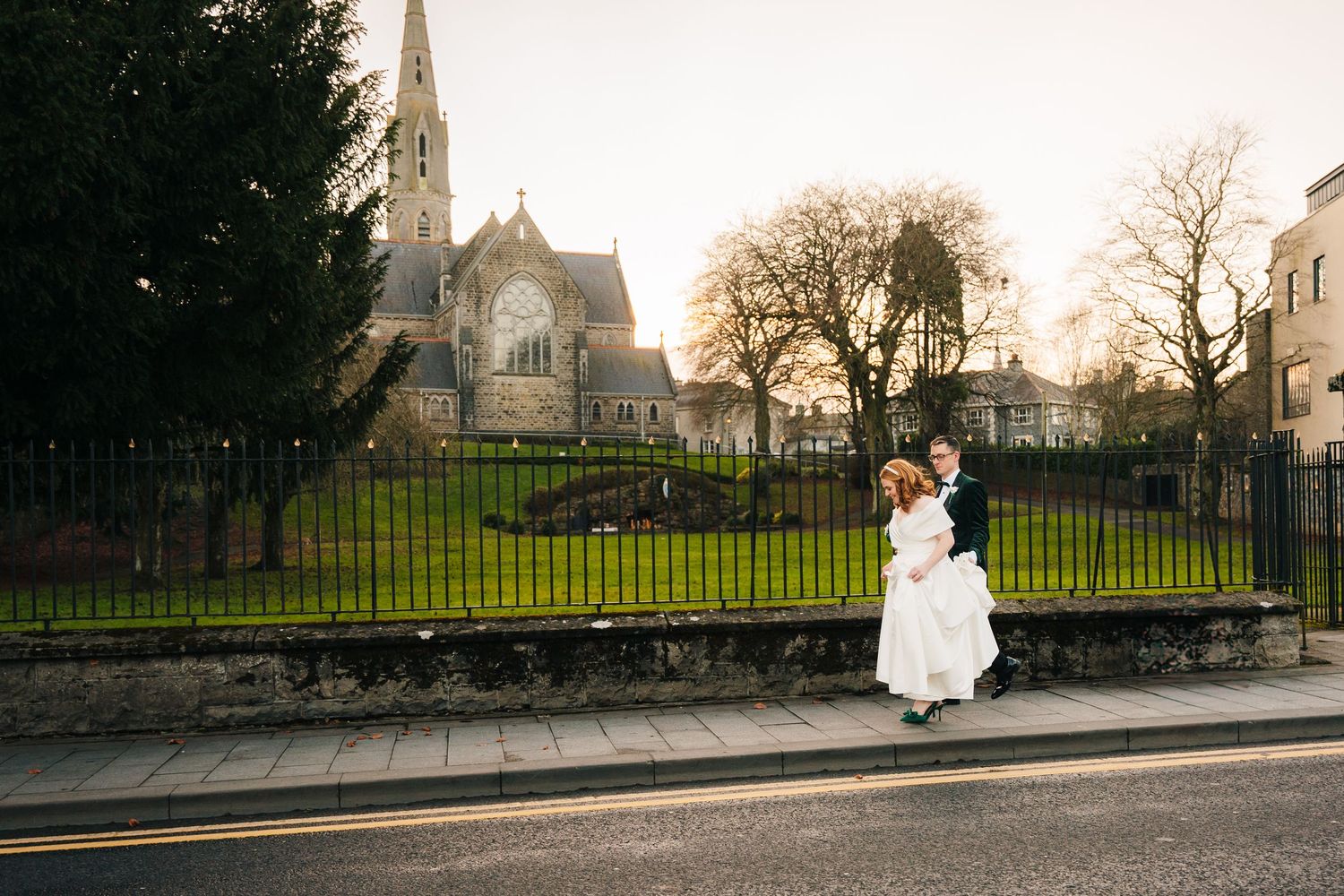 A winter wedding portrait with a church and trees in the background at dusk.  Wedding PHOTOGRAPHER Trim Castle