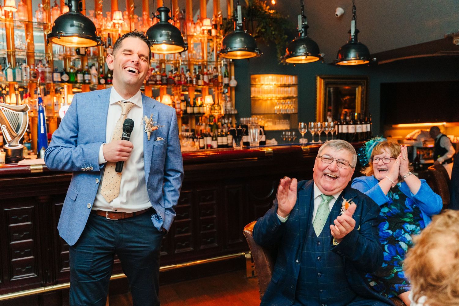 Wedding guests laughing and celebrating during a reception at a dimly lit bar venue. Marco Pierre Dublin Wedding Photographer